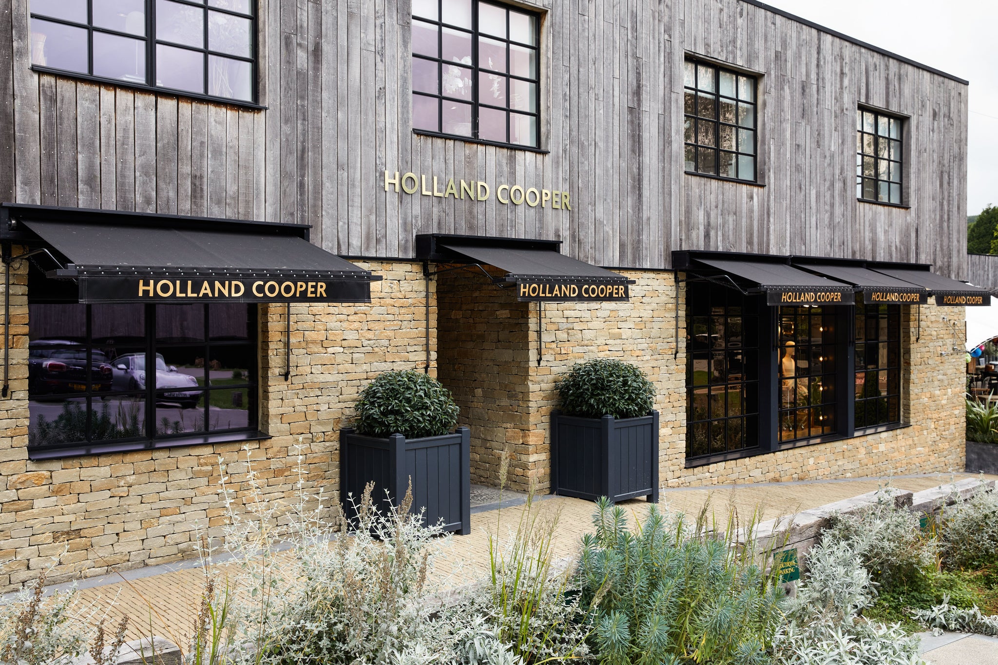 Holland Cooper Womens Boutique Store with gold lettering and cotswold yellow stone building with black glass door