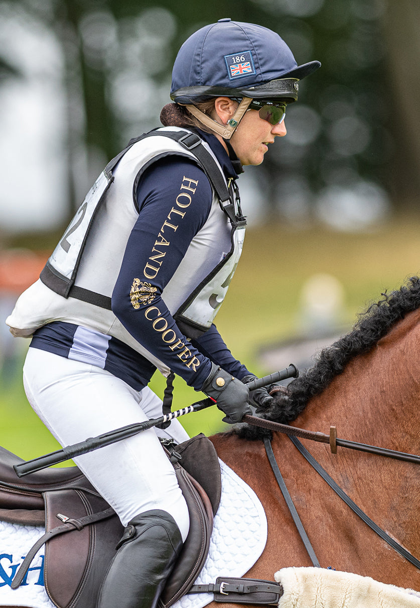 Laura Collett, riding horse in Holland Cooper navy base layer, white breeches, navy helmet on brown horse, London 52