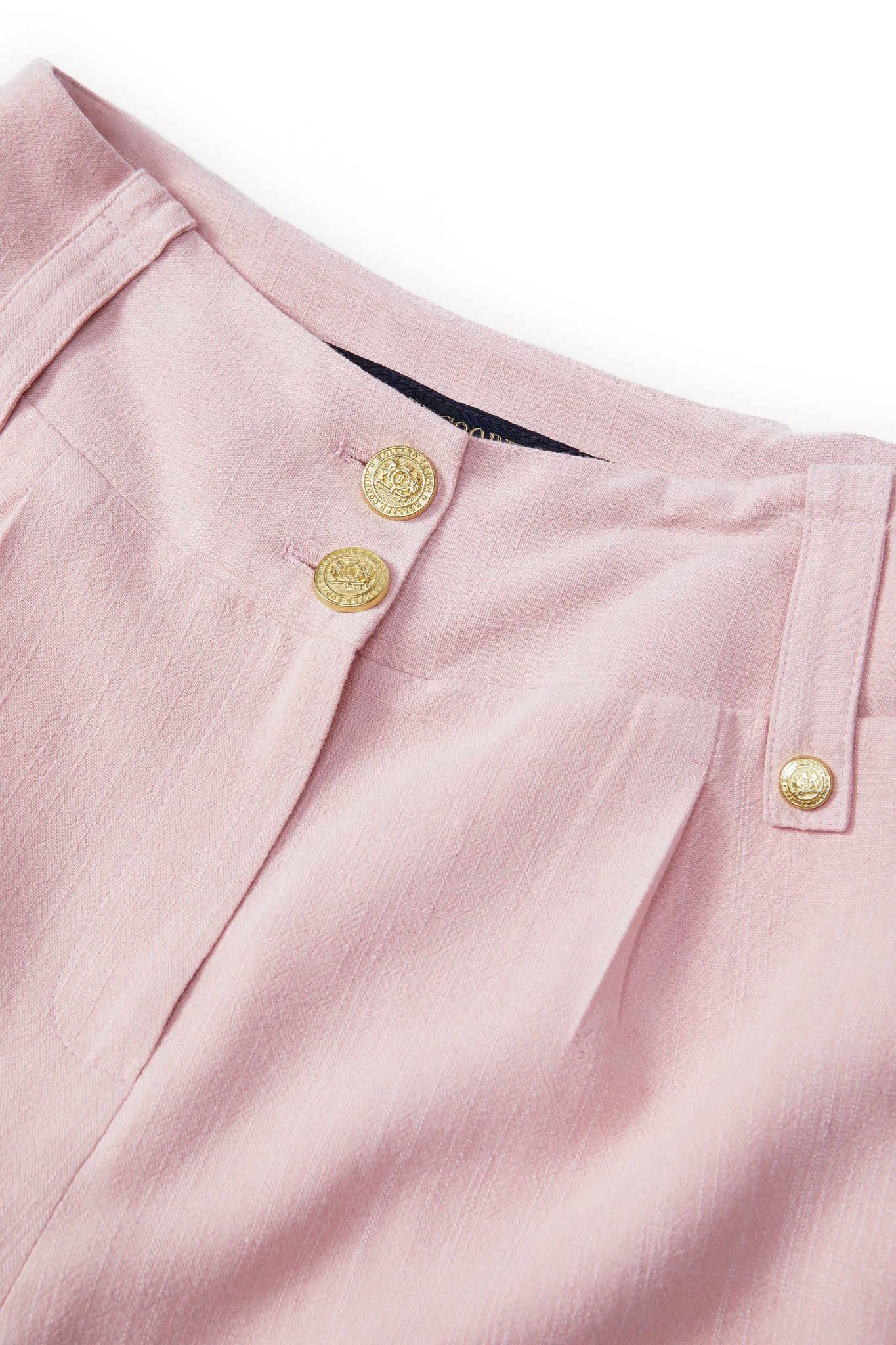 gold stud button detail of womens light pink linen tailored shorts with two single knife pleats and centre front zip fly fastening
