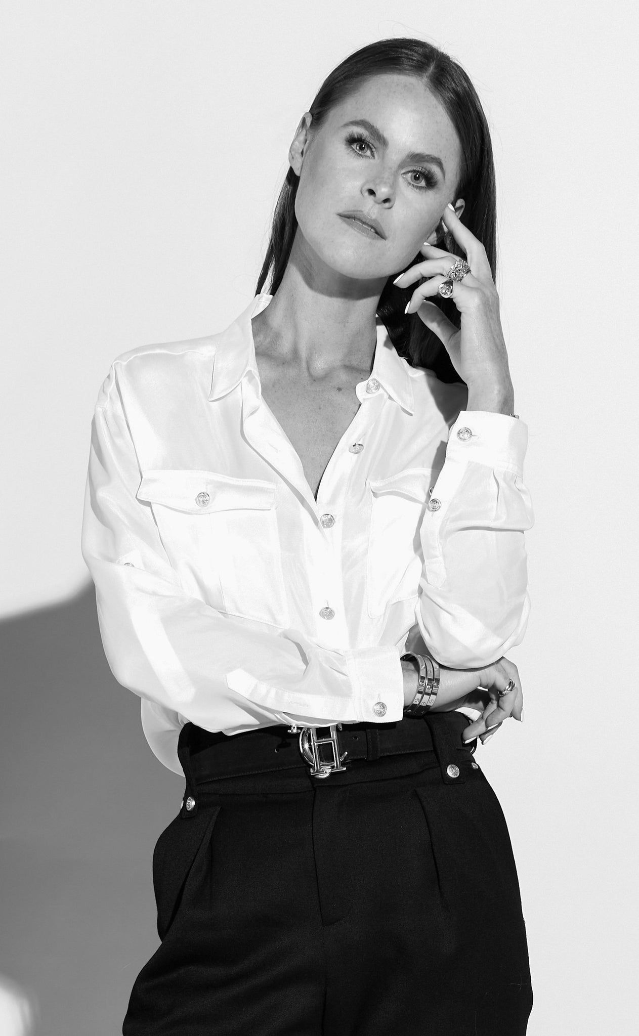 Black and white image of Jade Holland Cooper, owner of Holland Cooper, stood in studio in a relaxed fit shirt and high waisted peg trousers 