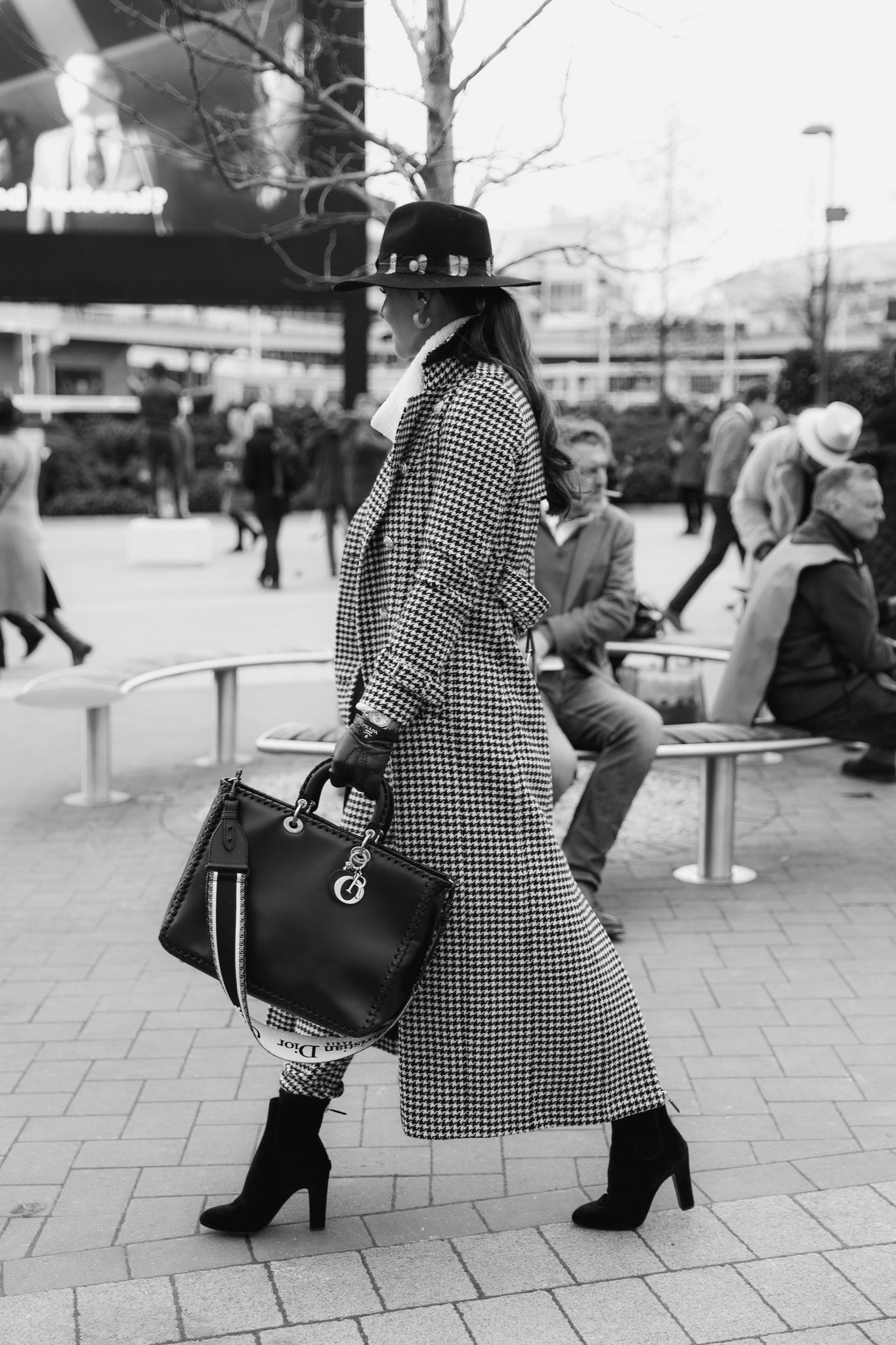 Black and White image of women wearing tribly hat, houndstooth coat carrying black bag