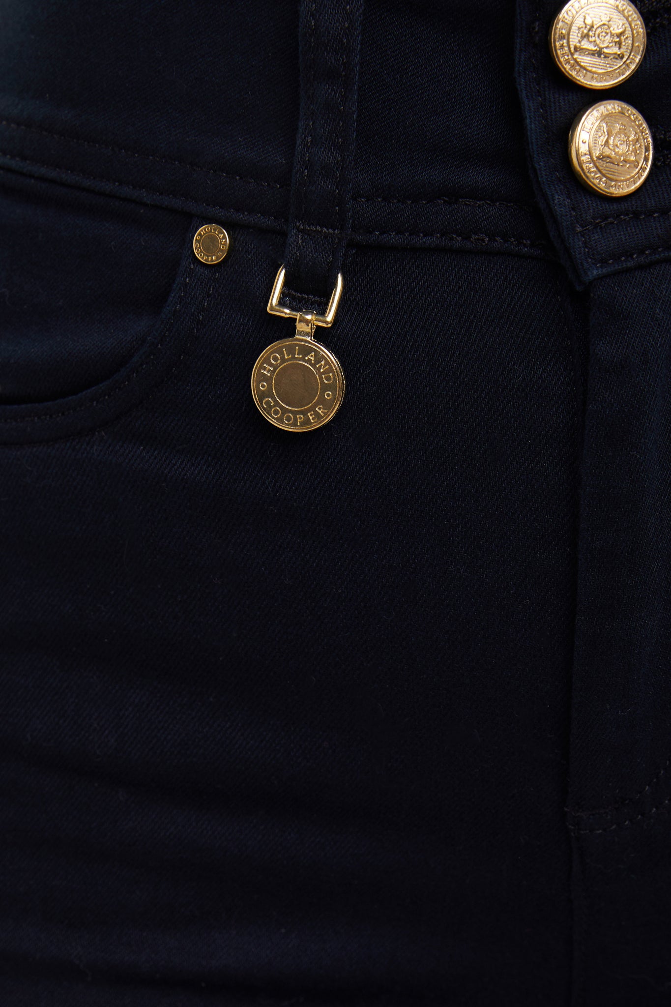gold charm on belt loop on womens high rise navy denim skinny stretch jean with jodhpur style seams and two open pockets to the front with hc embroidery on front left pocket