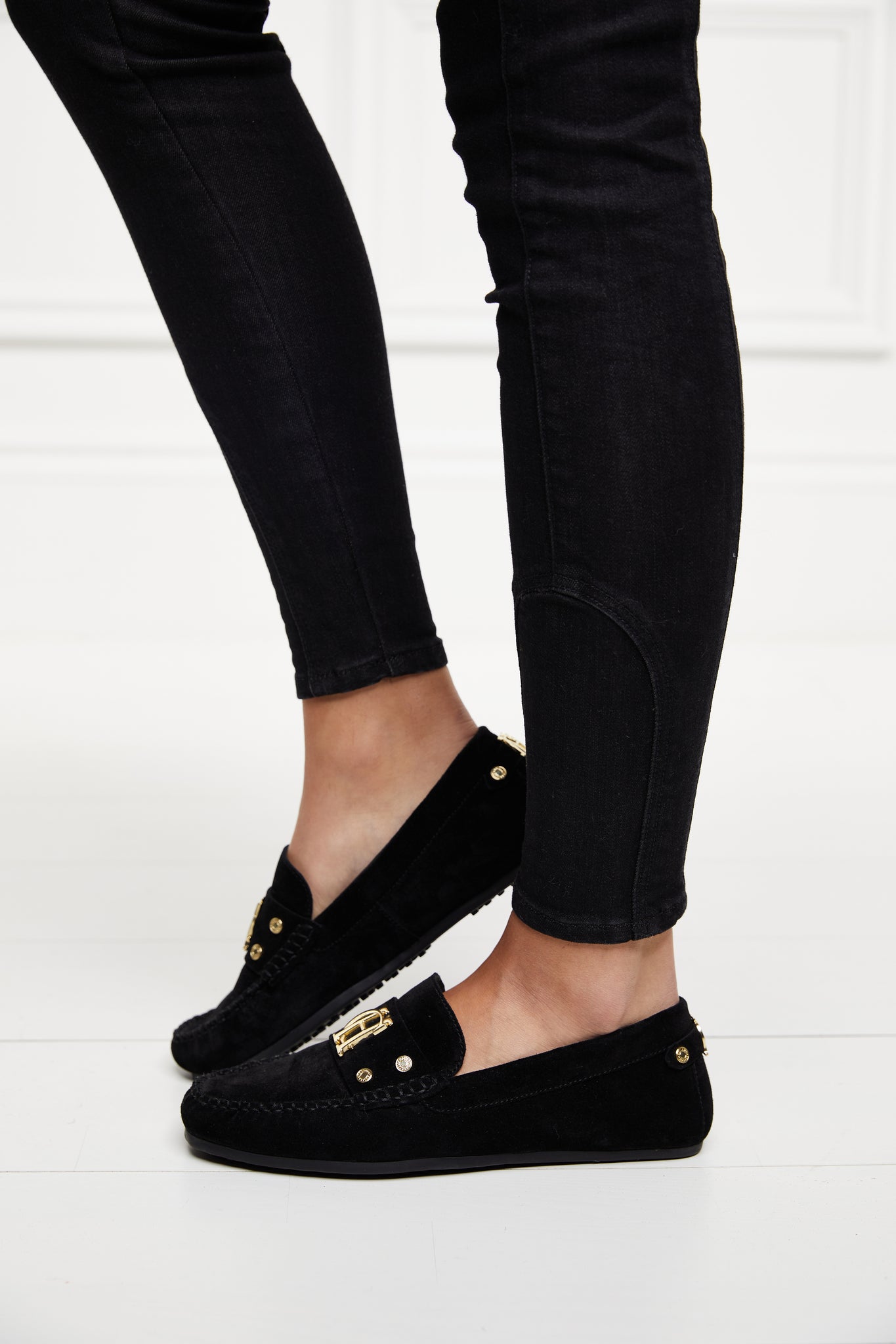 classic black suede loafers with a leather sole and top stitching details and gold hardware paired with skinny black jeans
