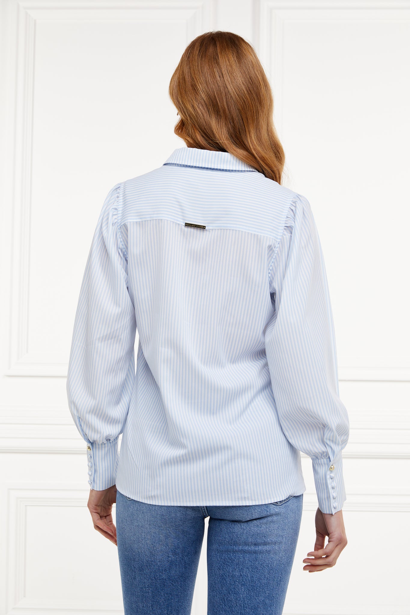 back image of classic fitting shirt with long sleeves and subtle puffy shoulders with thin blue and white stipe print design with extra long cuffs and rounded collar detailed with fabric buttons 