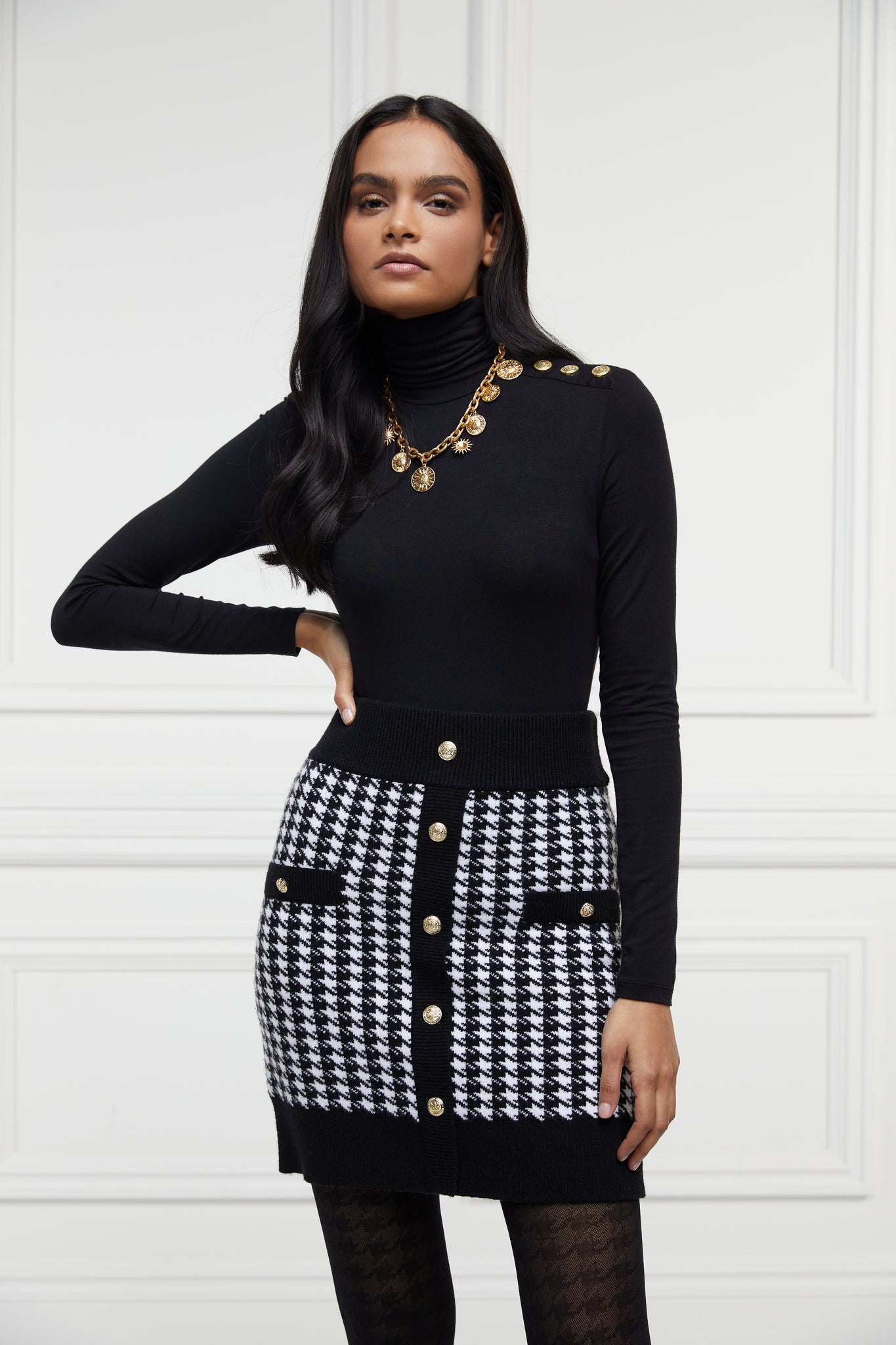 womens knitted mini skirt in back and white houndstooth pattern with contrast ribbed waistband centre front panel welt pockets and hem with gold button detail down the front and on each pocket