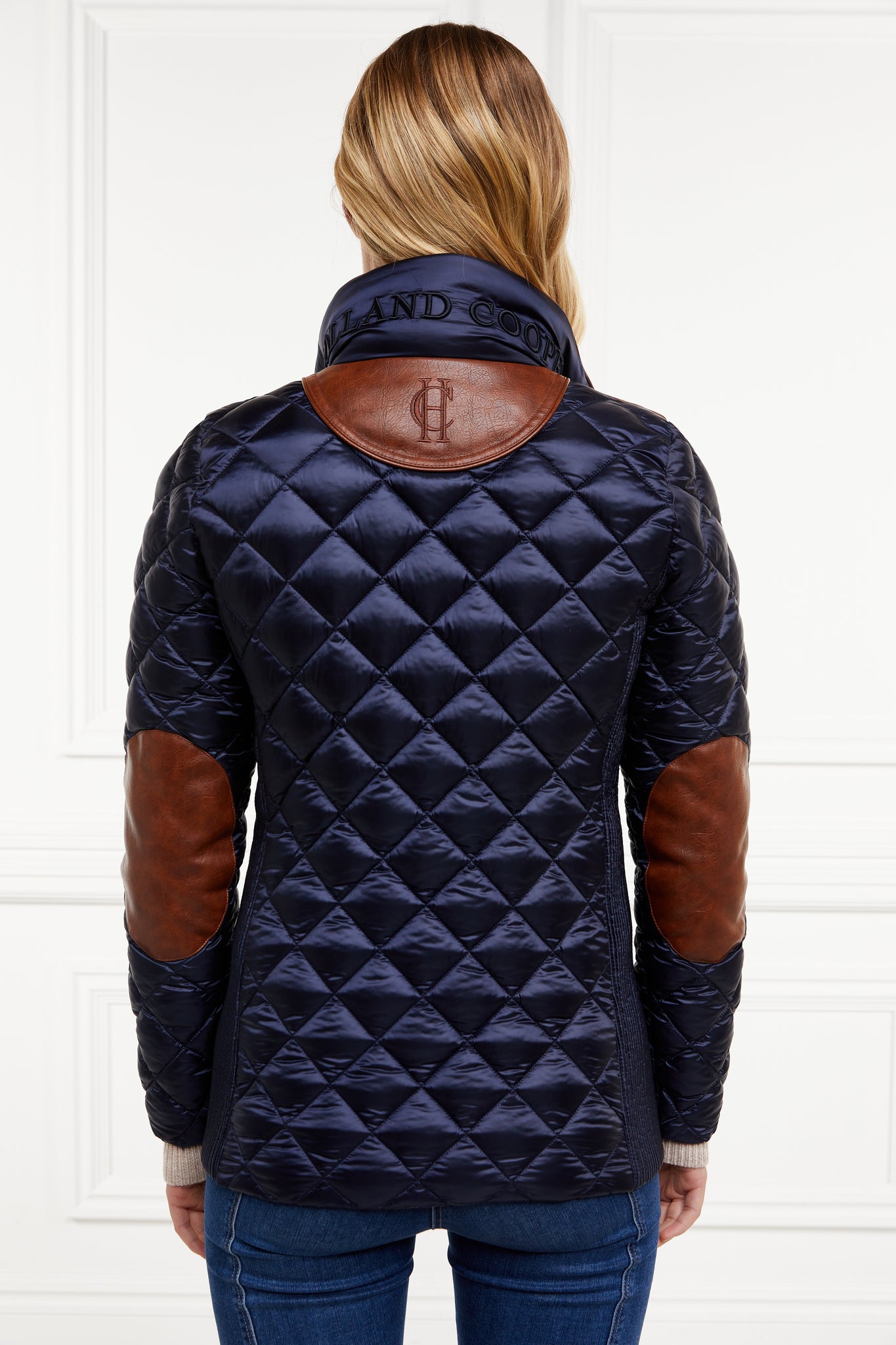 back of womens diamond quilted navy jacket with contrast tan leather elbow and shoulder pads large front pockets and shirred side panels