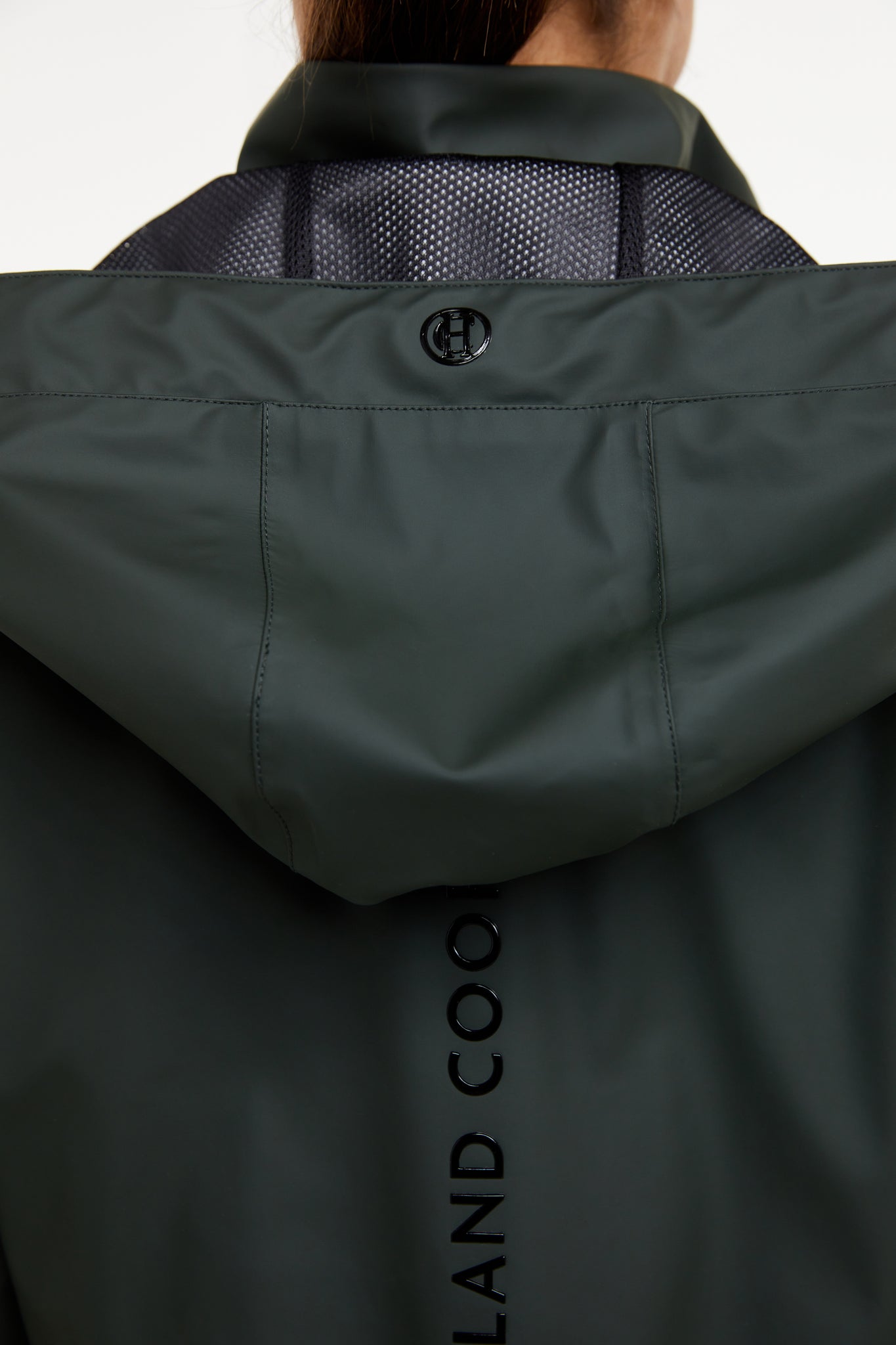 detail of womens green hooded rain coat with black hardware 