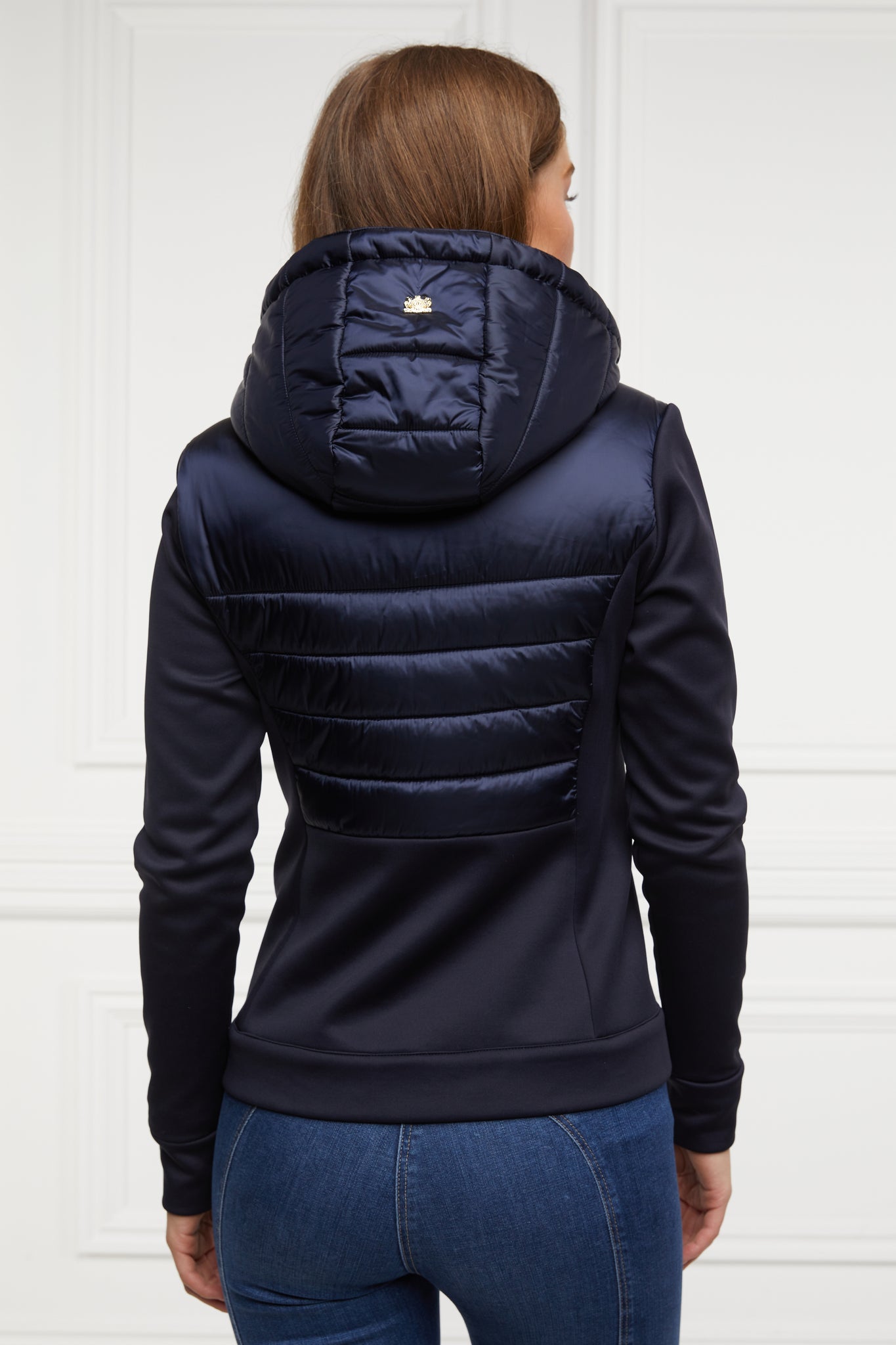 back of hooded hybrid jacket in navy with jersey panels on the waist and sleeves and Sorona eco down fill on hood front and back body panels finished with rubbed zip fastening in black and two side pockets with the same zip fastenings