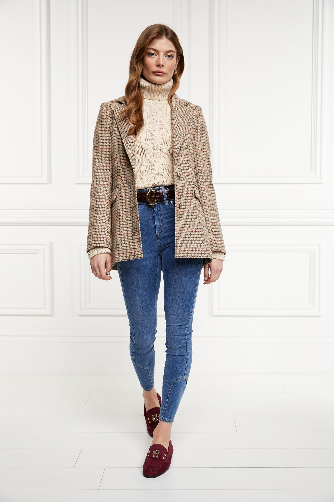 a chunky cable knit roll neck jumper in oatmeal with dropped shoulders and thick ribbed cable trims and gold buttons on cuffs and collar paired with a single breasted blazer in charlton tweed