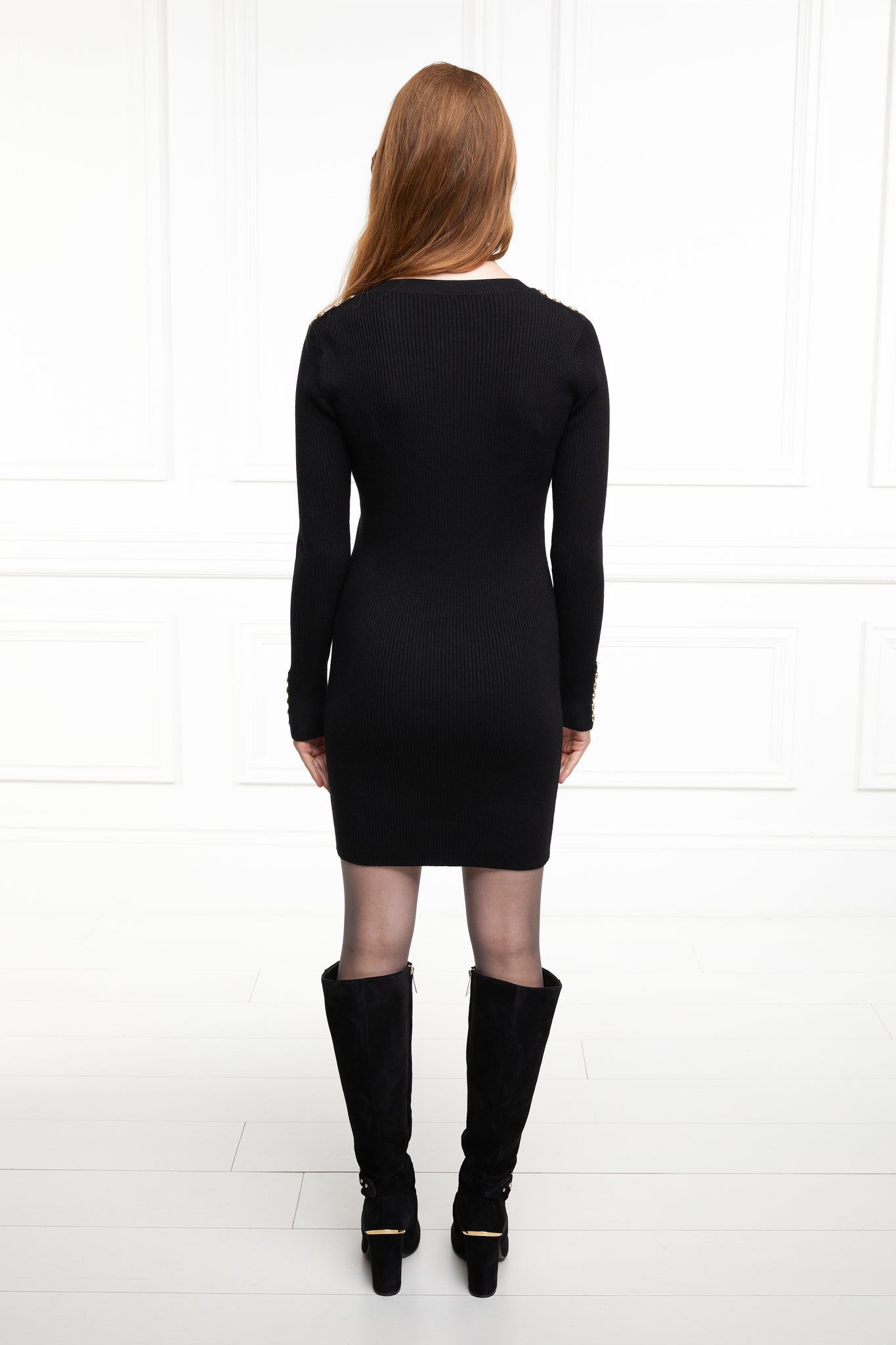 back of womens slim fit crew neck long sleeve knitted dress in black with gold button detail down the centre front and two welt pockets on chest and two on the hips with gold buttons on the centre of each pocket
