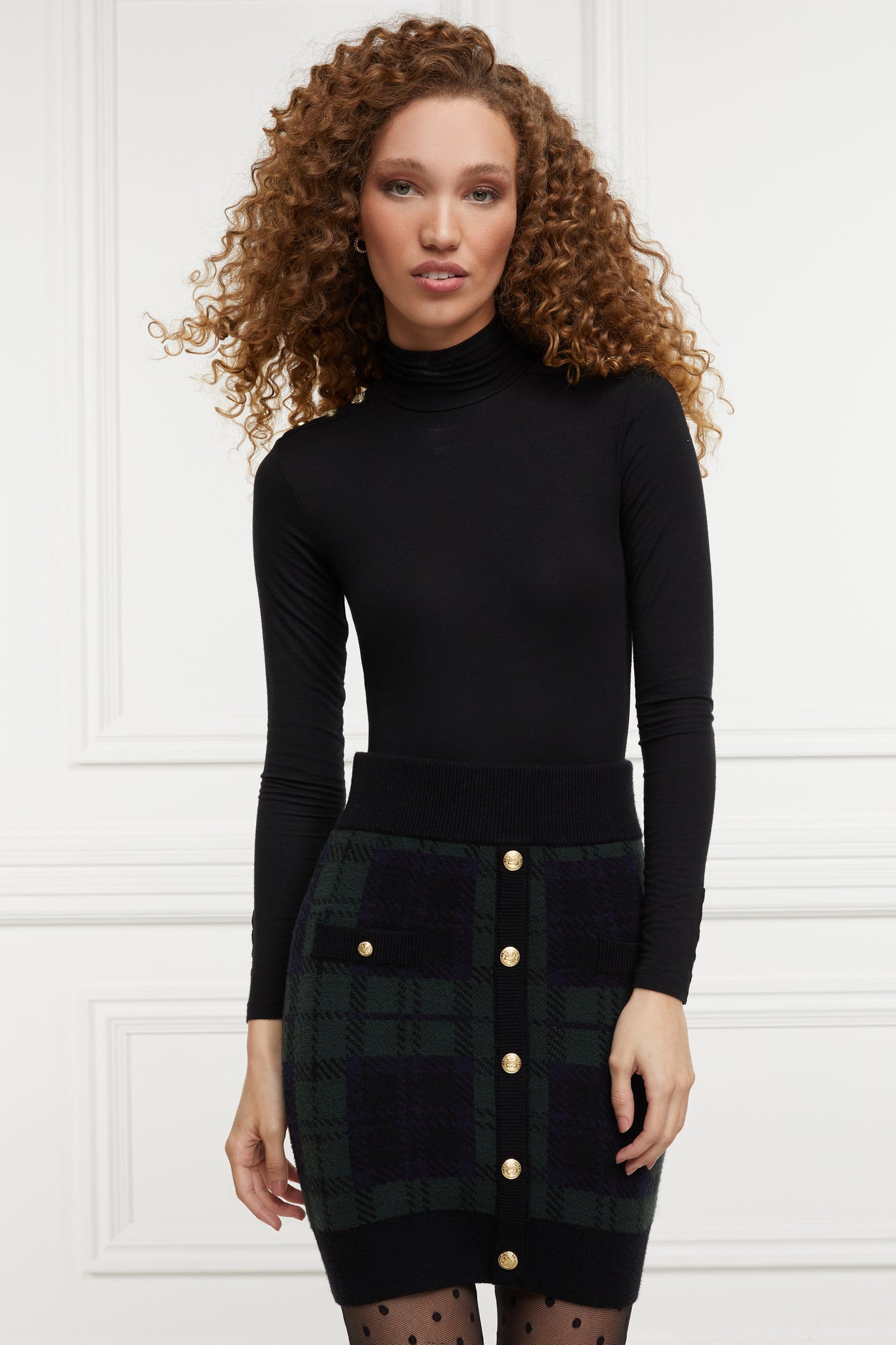 womens knitted mini skirt in green back and navy blackwatch pattern with contrast eibbed waistband centre front panel welt pockets and hem with gold button detail down the front and on each pocket