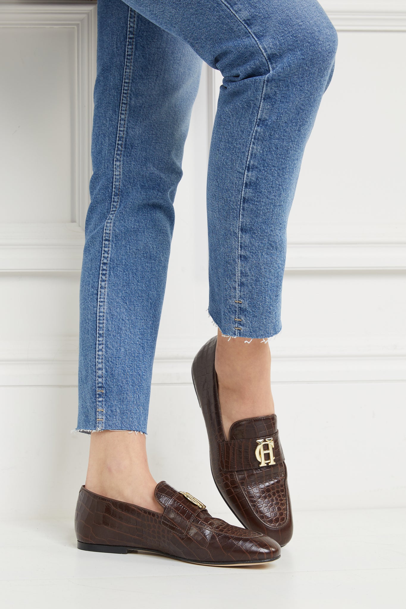 brown croc embossed leather loafers with a slightly pointed toe and gold hardware to the top, paired with denim slim jeans