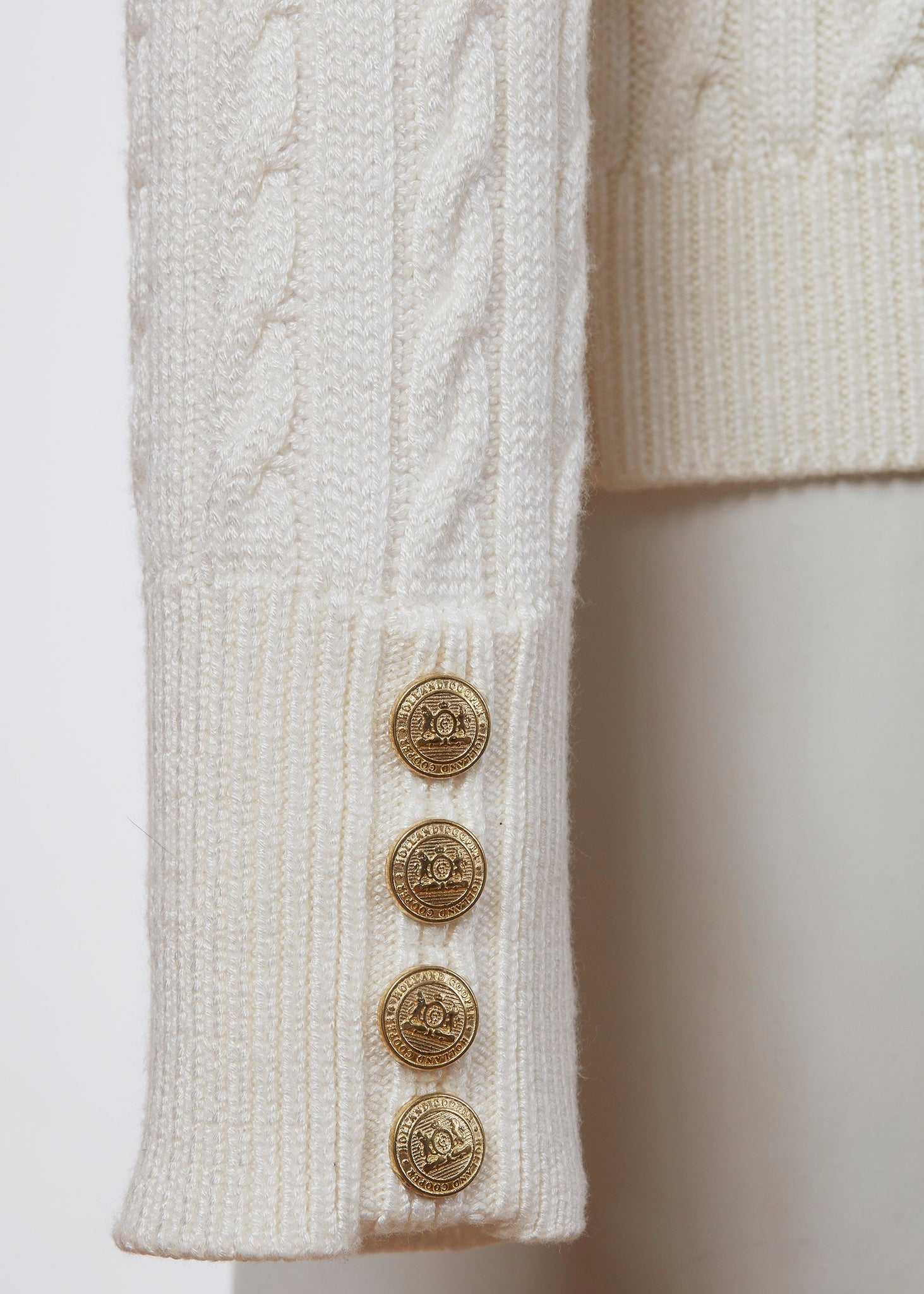 gold button detail on cuff of womens cable knit jumper in white with ribbed roll neck cuffs and hem