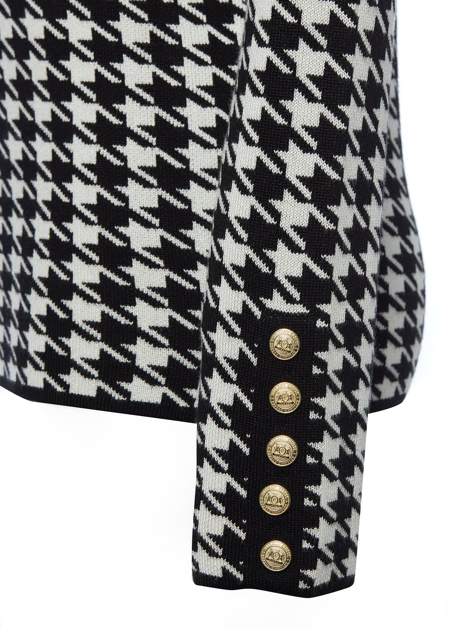gold button detail on cuffs of a classic black and white houndstooth jumper with contrast black roll neck collar