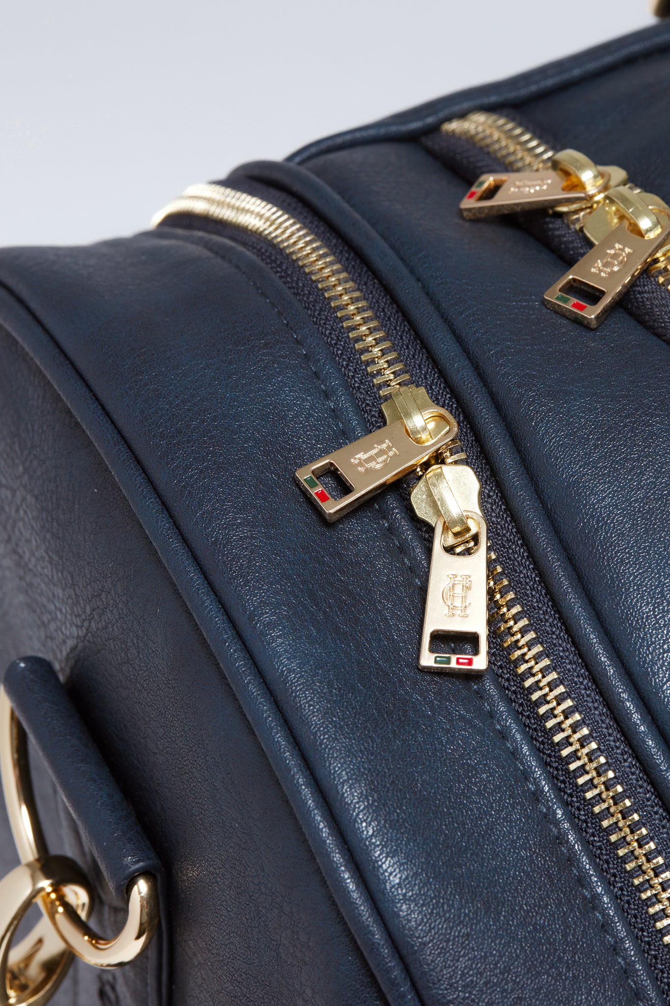 close up of gold zips on side compartments on navy faux leather equestrian kit bag