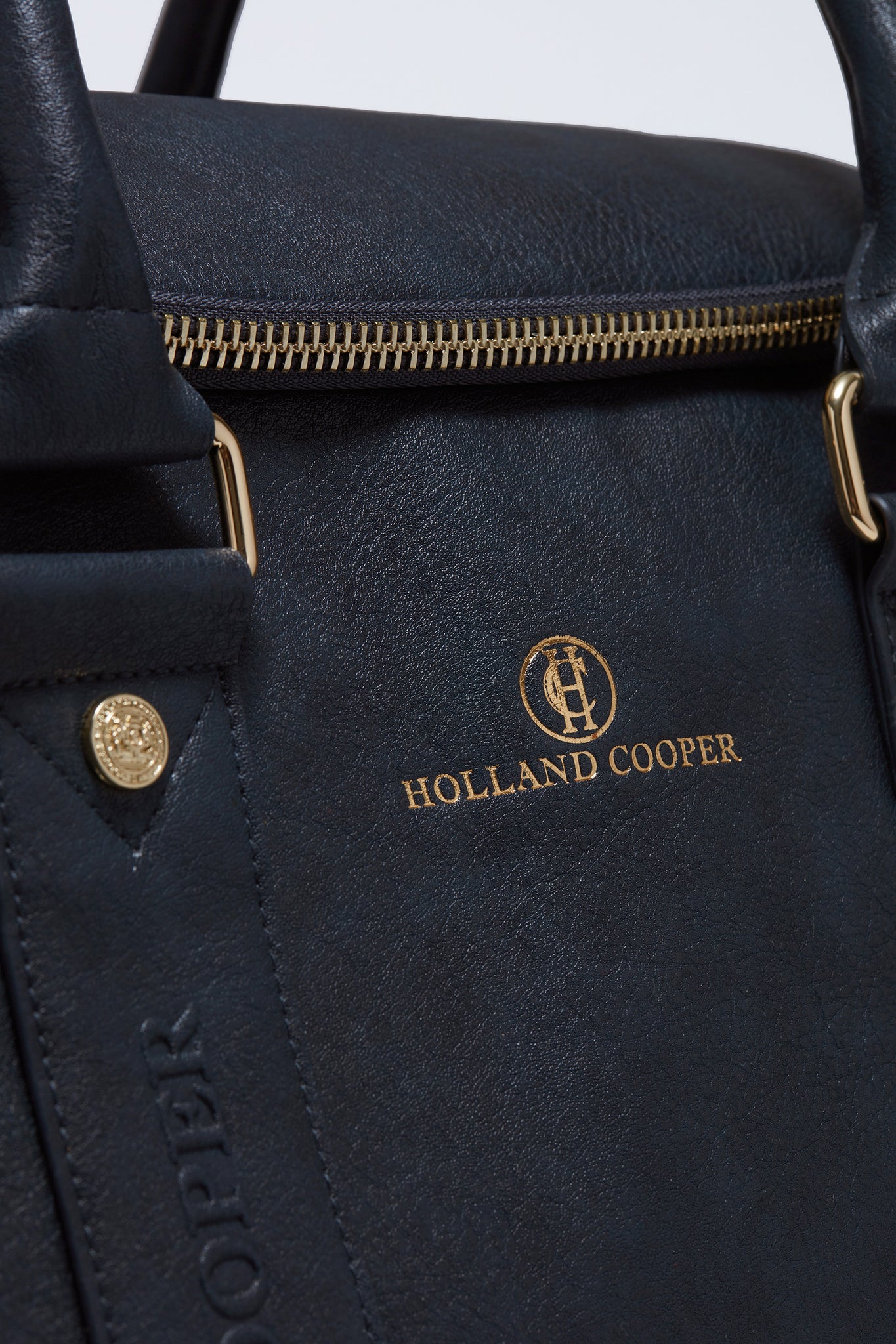 close up of gold embossed brand logo and zip on navy faux leather equestrian kit bag