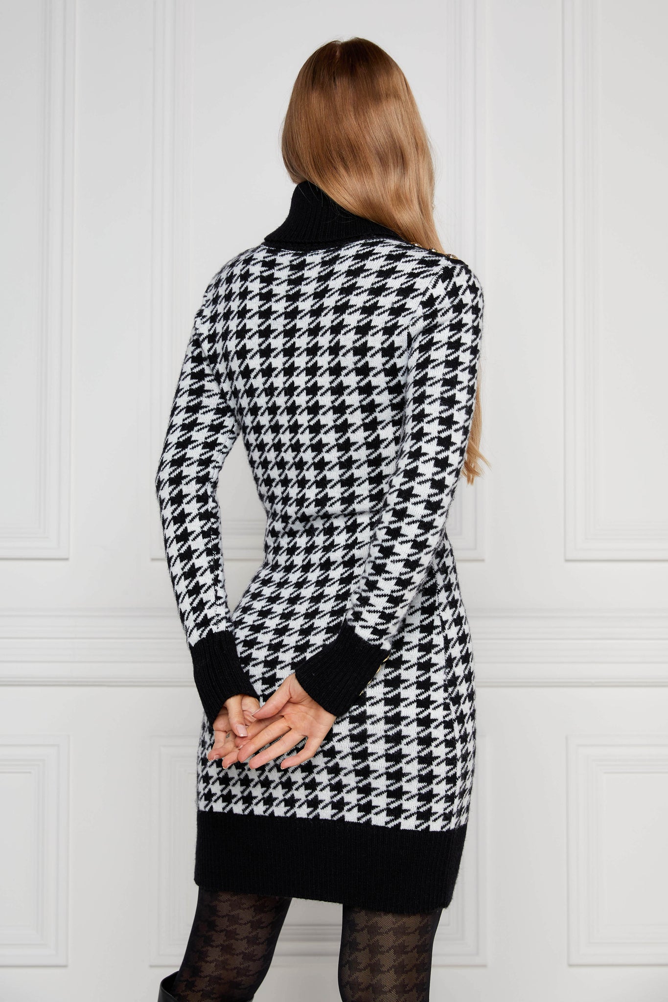 back of womens black and white houndstooth roll neck jumper dress with contrast black cuffs and ribbed hem with gold button detail on the cuffs and shoulders