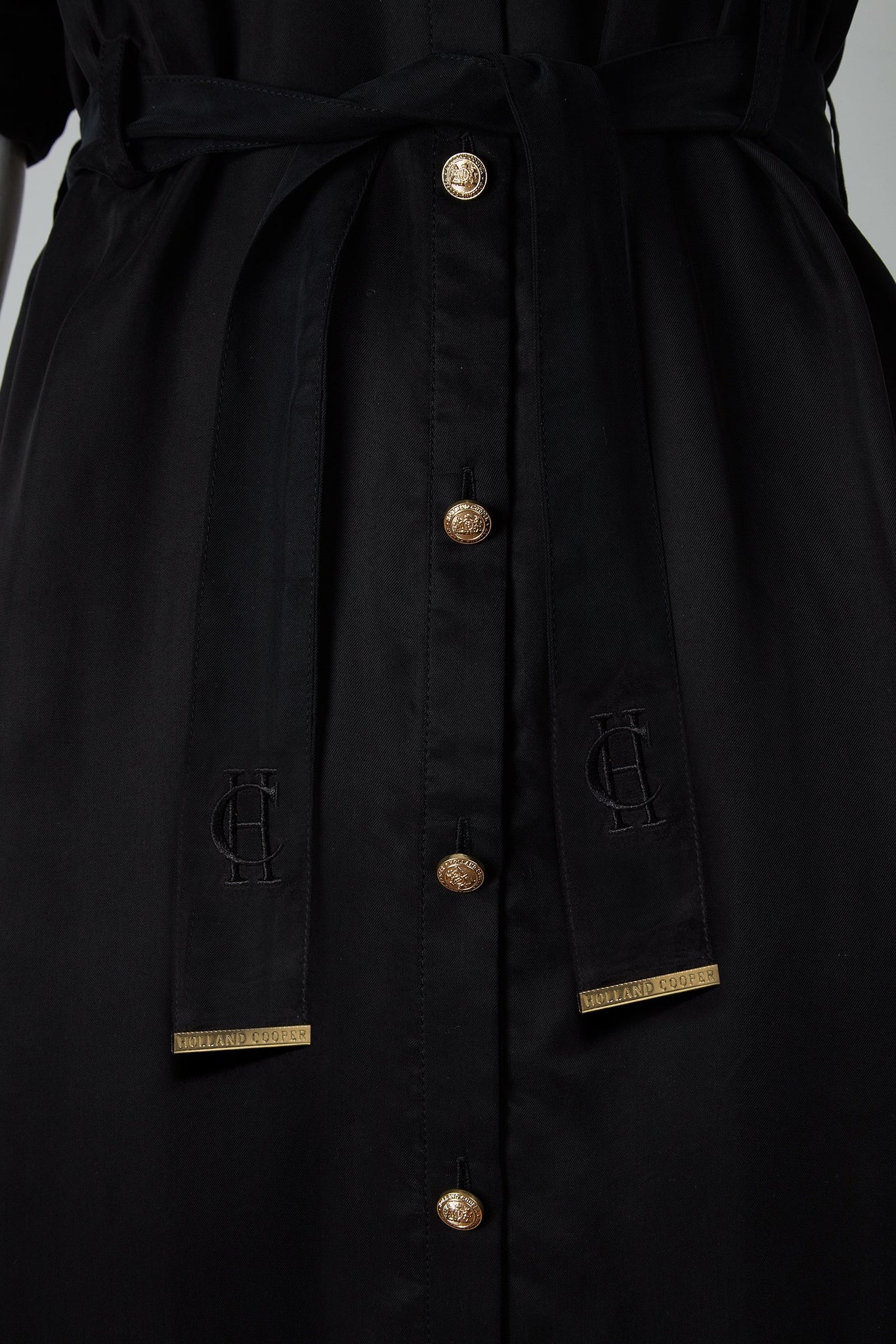 detail shot of gold buttons on womens black military midi shirt dress with tie around waist and gold buttons down the front