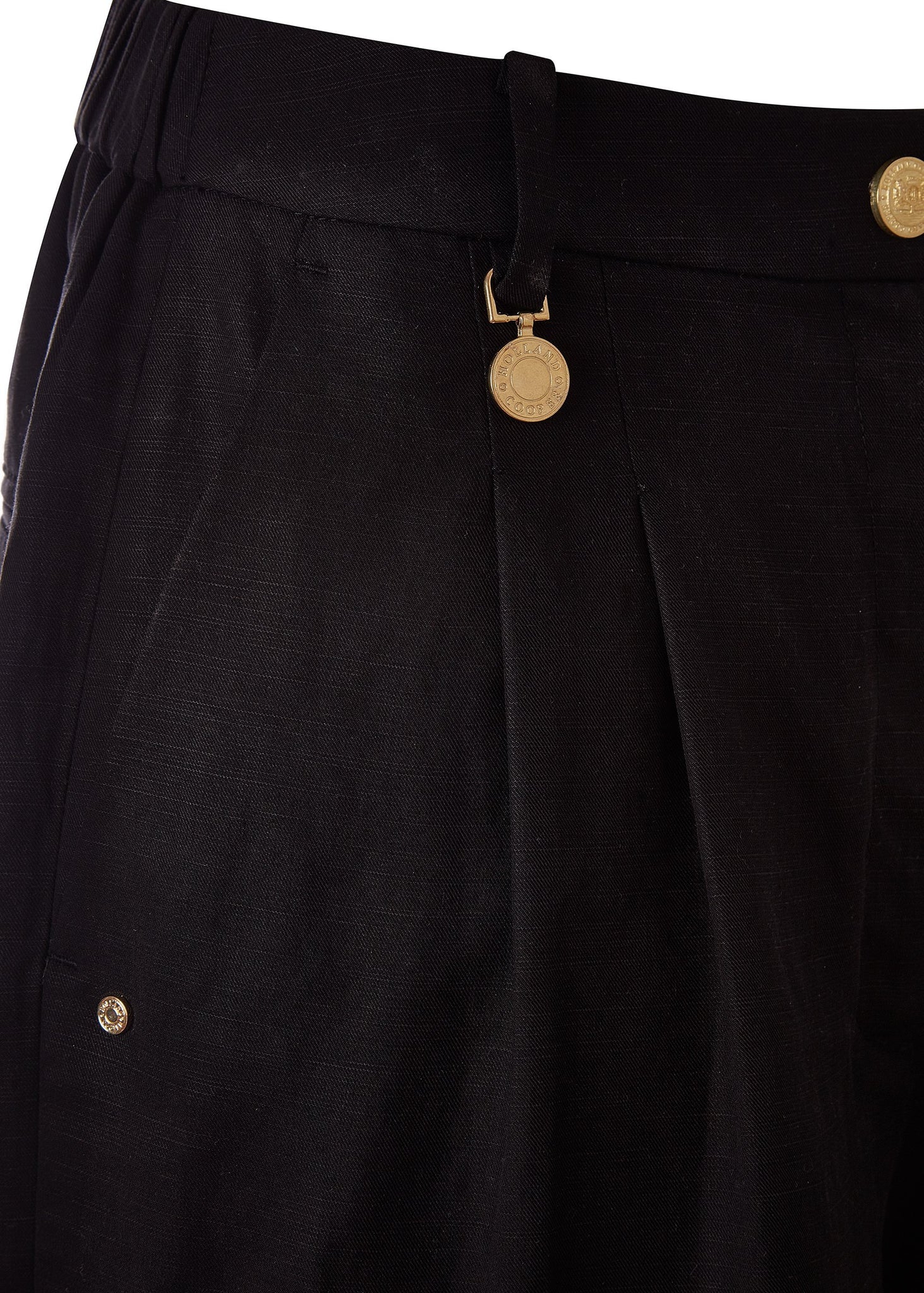 side pocket detail of womens black shorts with double front pleats and turned up hem with two open front pockets and centre front zip fly fastening and a signature gold hc button