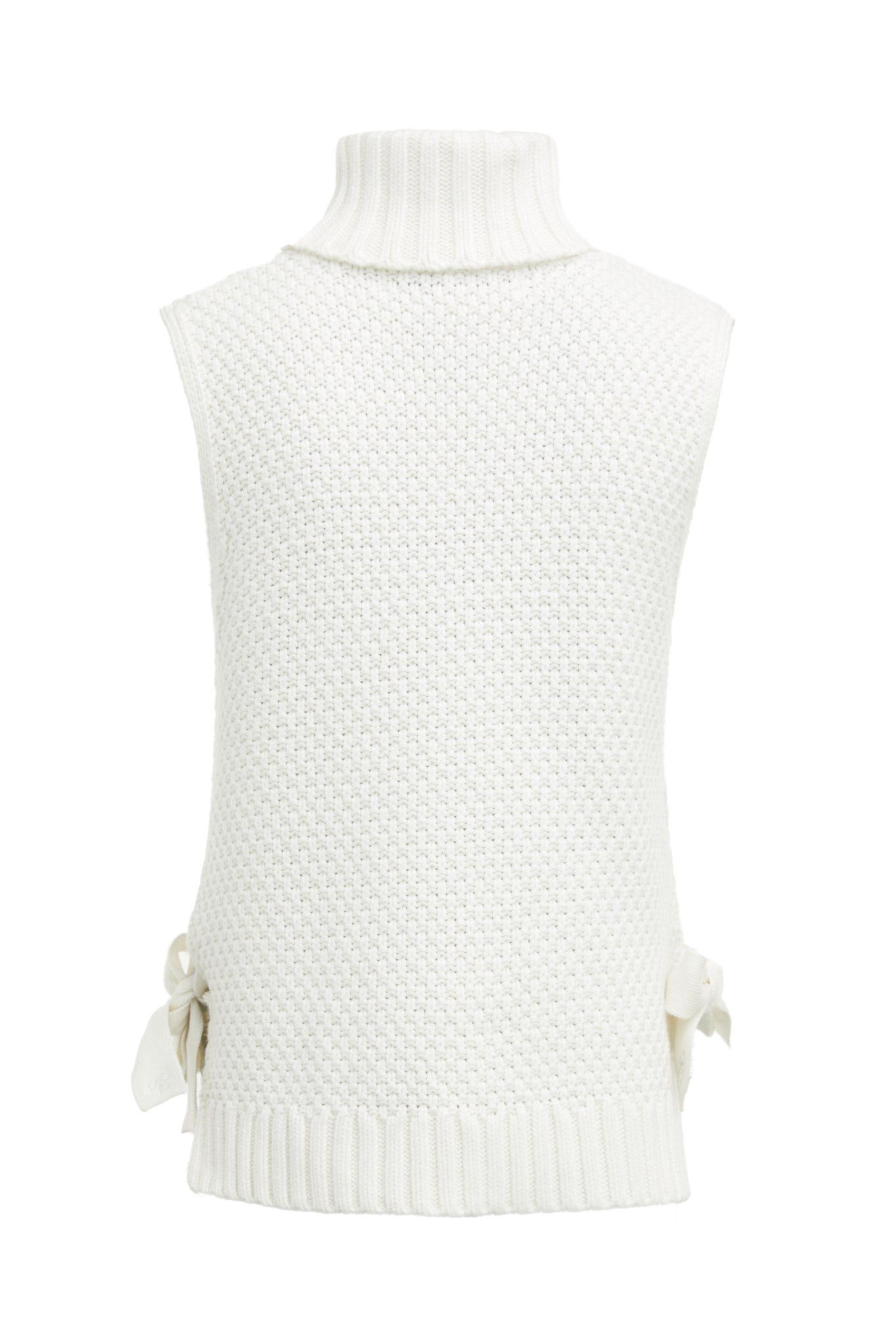 Back of sleeveless white chunky knit cable jumper with a roll neck and ties at each side 