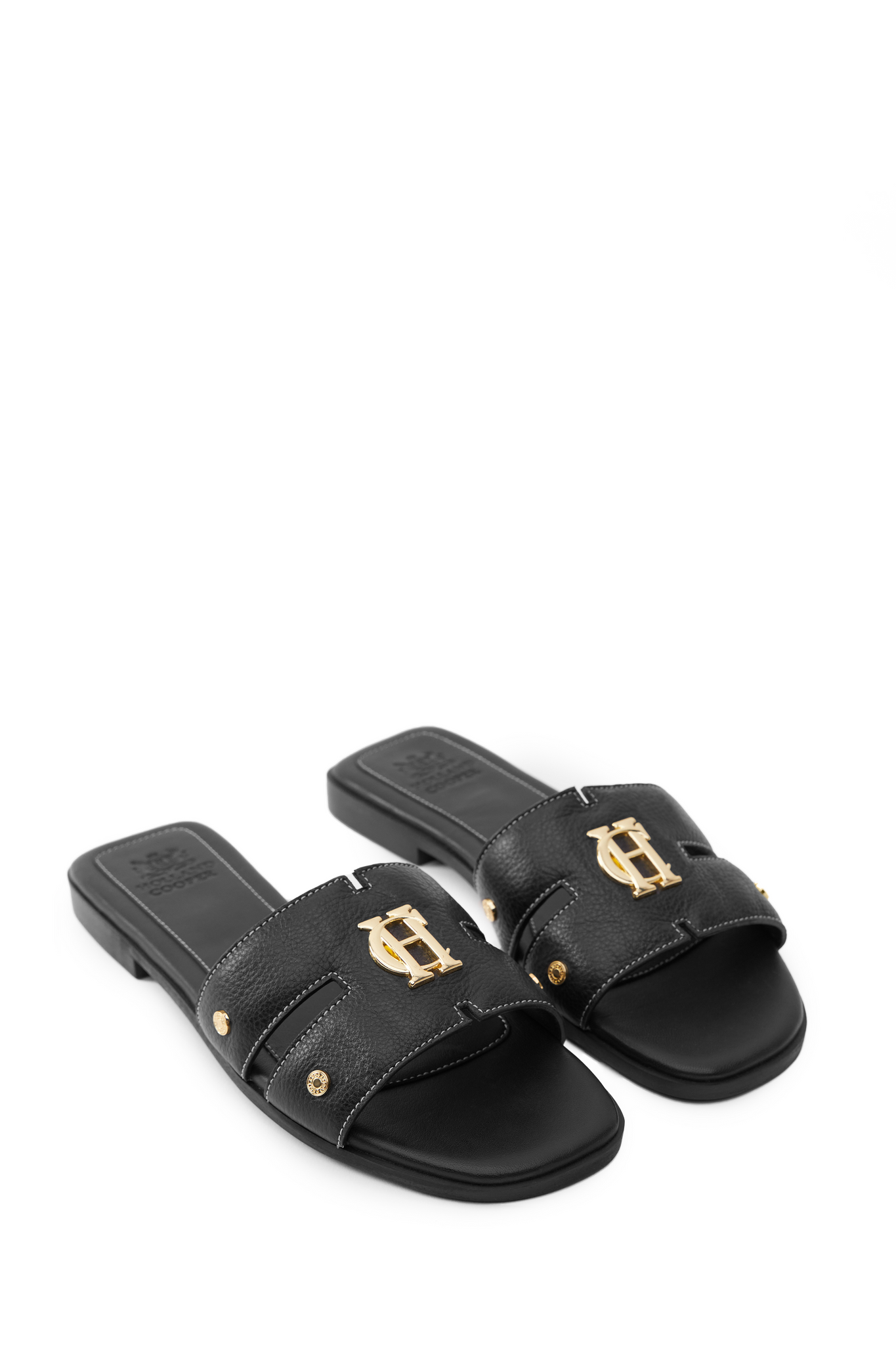 black leather sliders with contrast white stitching, a black leather sole and gold hardware