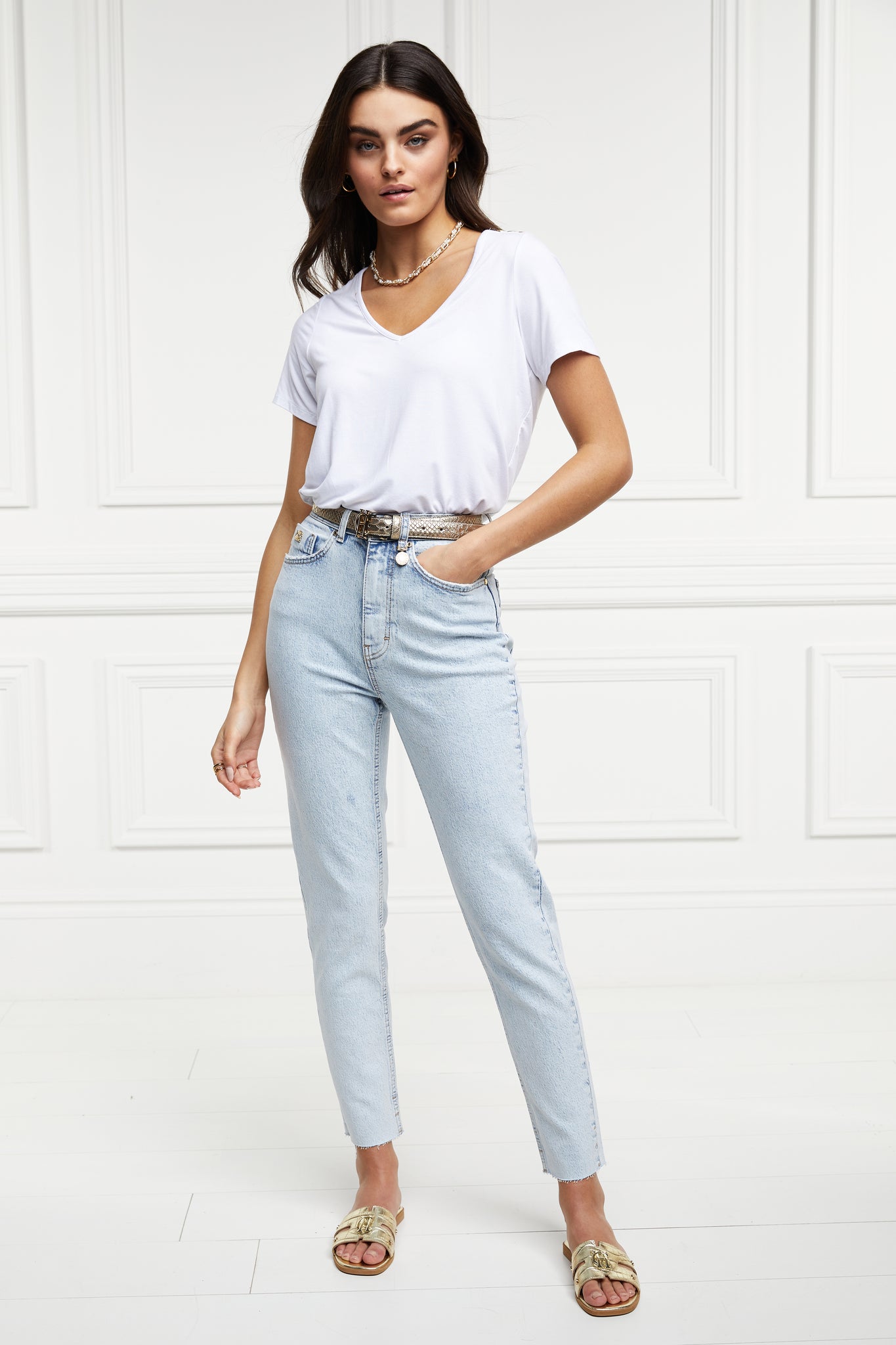 womens high rise light blue denim slim fit jean with raw hem and two open pockets on the front and back with gold stirrup charm to the belt loop
