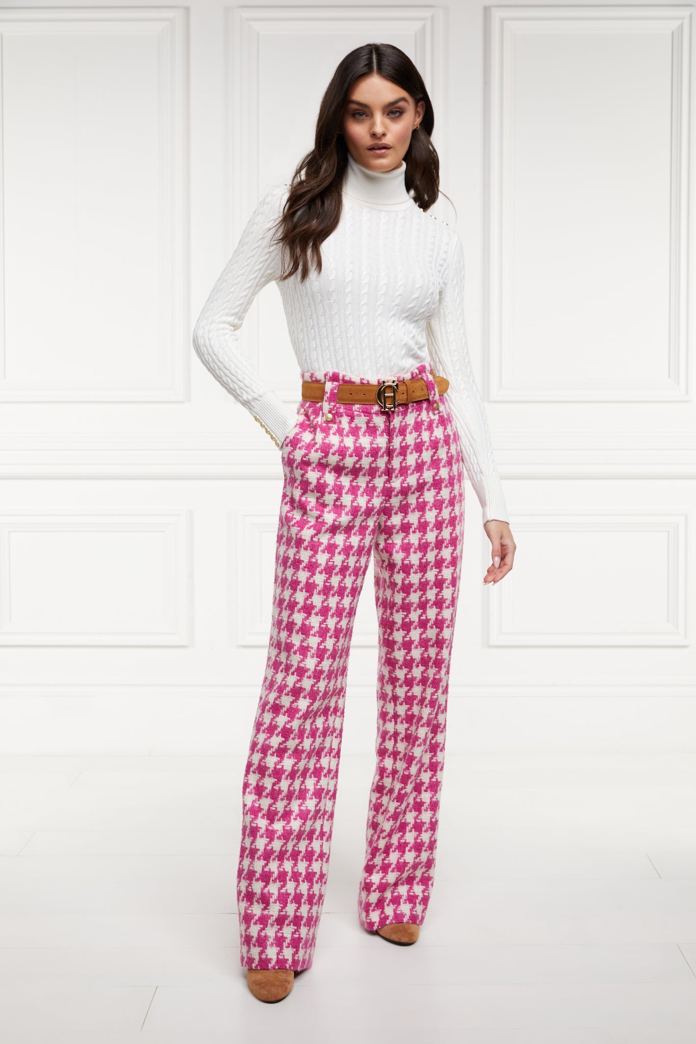 Women's hot pink houndstooth wool high waisted straight trousers with white roll neck cable knit top and tan suede belt