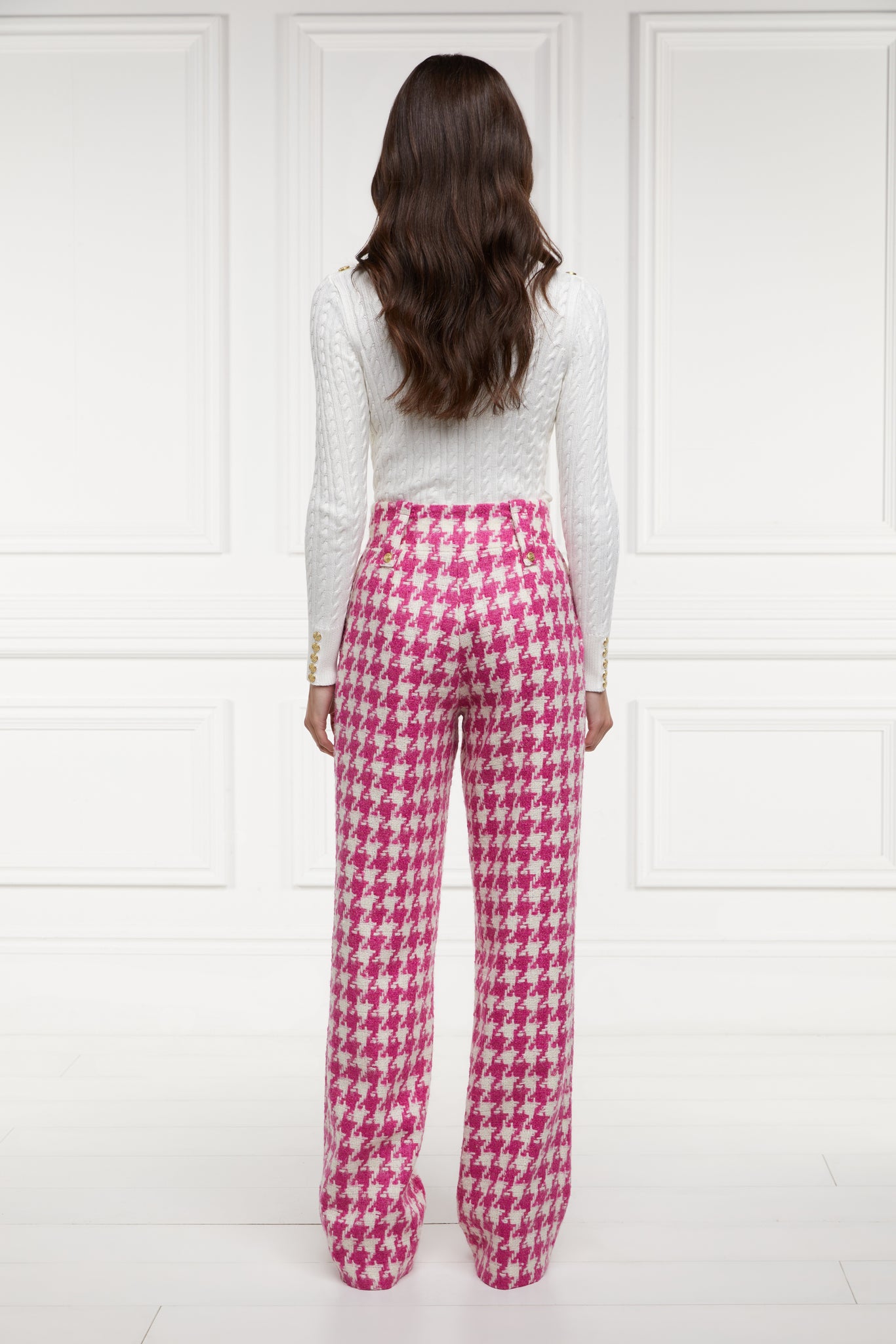 Back of Women's hot pink houndstooth wool high waisted straight trousers with white roll neck cable knit top