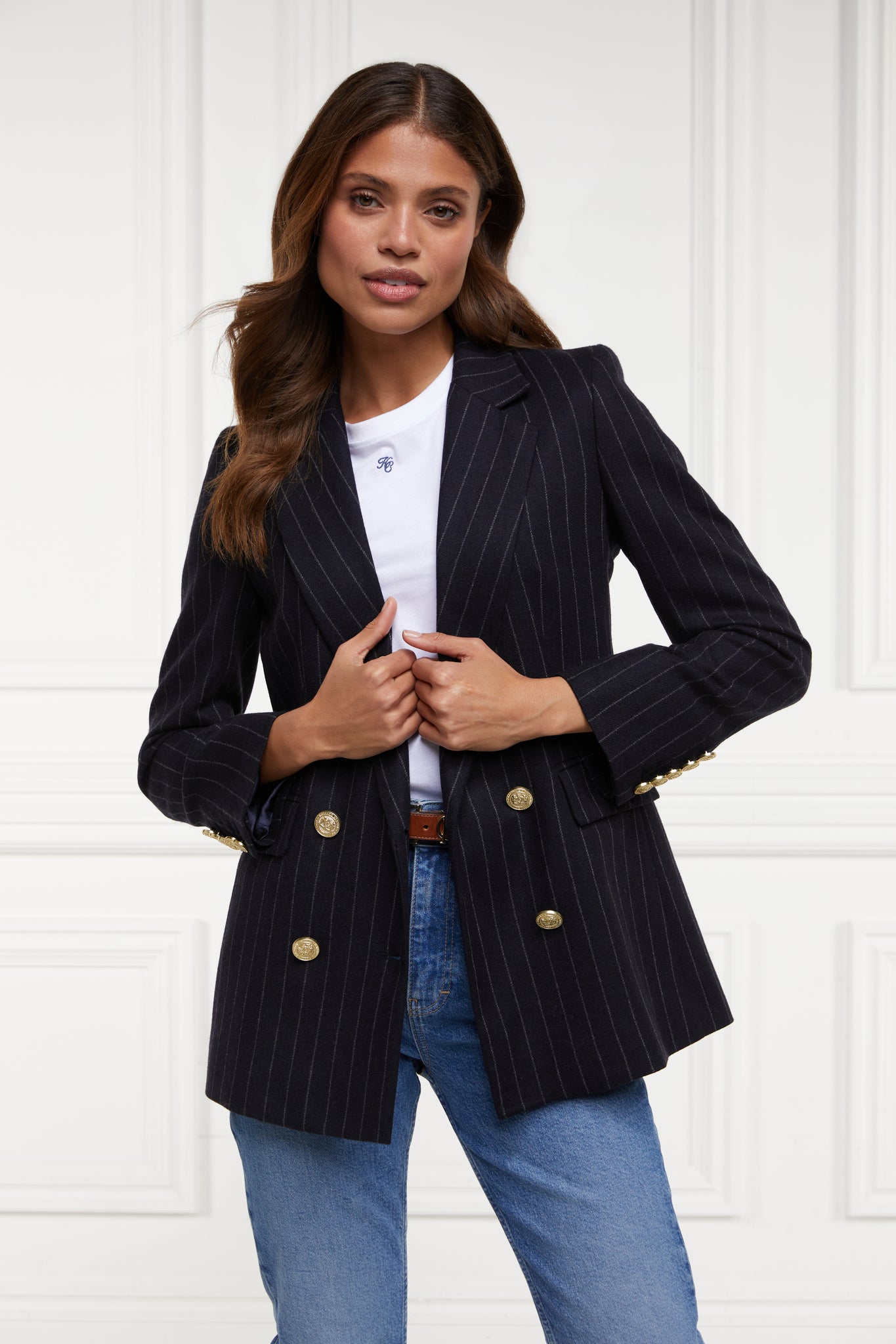 double breasted wool blazer in navy and cream chalk pinstripe with two hip pockets and gold button detials down front and on cuffs and handmade in the uk worn with white tee and light wash denim jeans