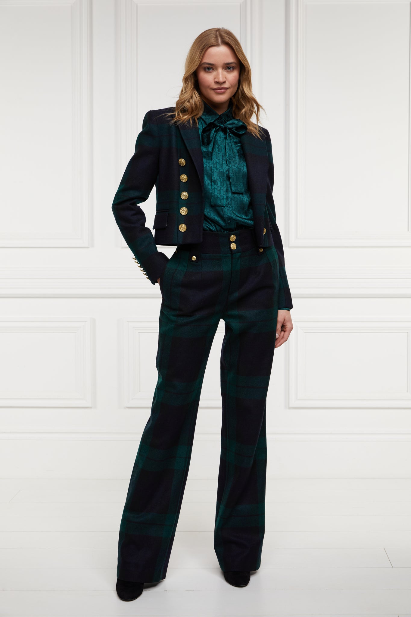 British made tailored cropped jacket in navy and green blackwatch tarten with welt pockets and gold button detail down the front and on sleeves worn with green silk shirt and tailored trousers in blackwatch