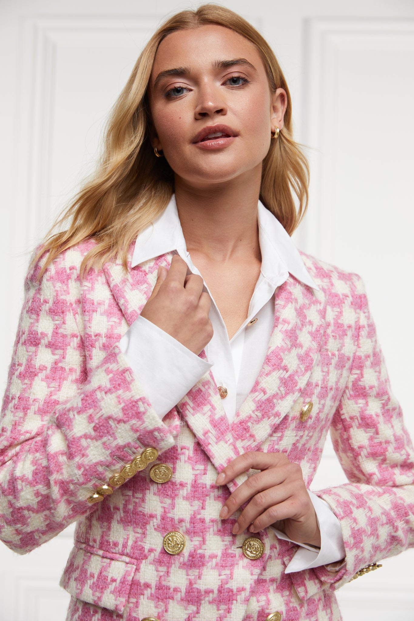pink and white large scale houndstooth fitted blazer double breasted style but with only single button fastening to the one central button for more form fitted tailored look finished with two pockets at hips and gold button details on front and cuffs