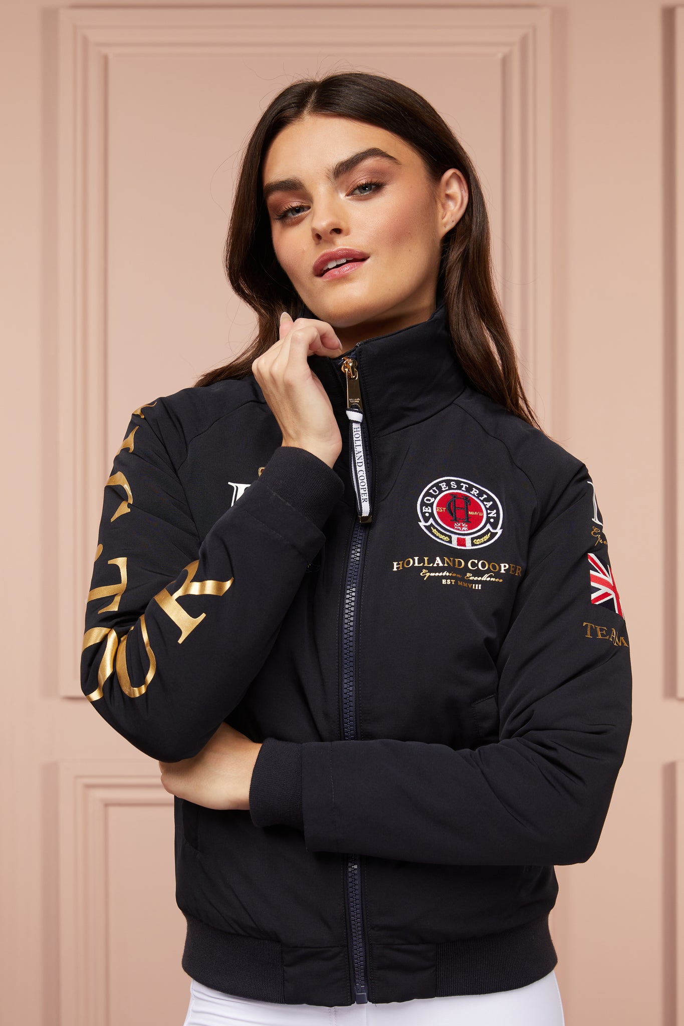 womens bomber style water resistant riding jacket in navy lined with fleece with elasticated ribbed cuffs and hem and covered in holland cooper equestrian graphic prints