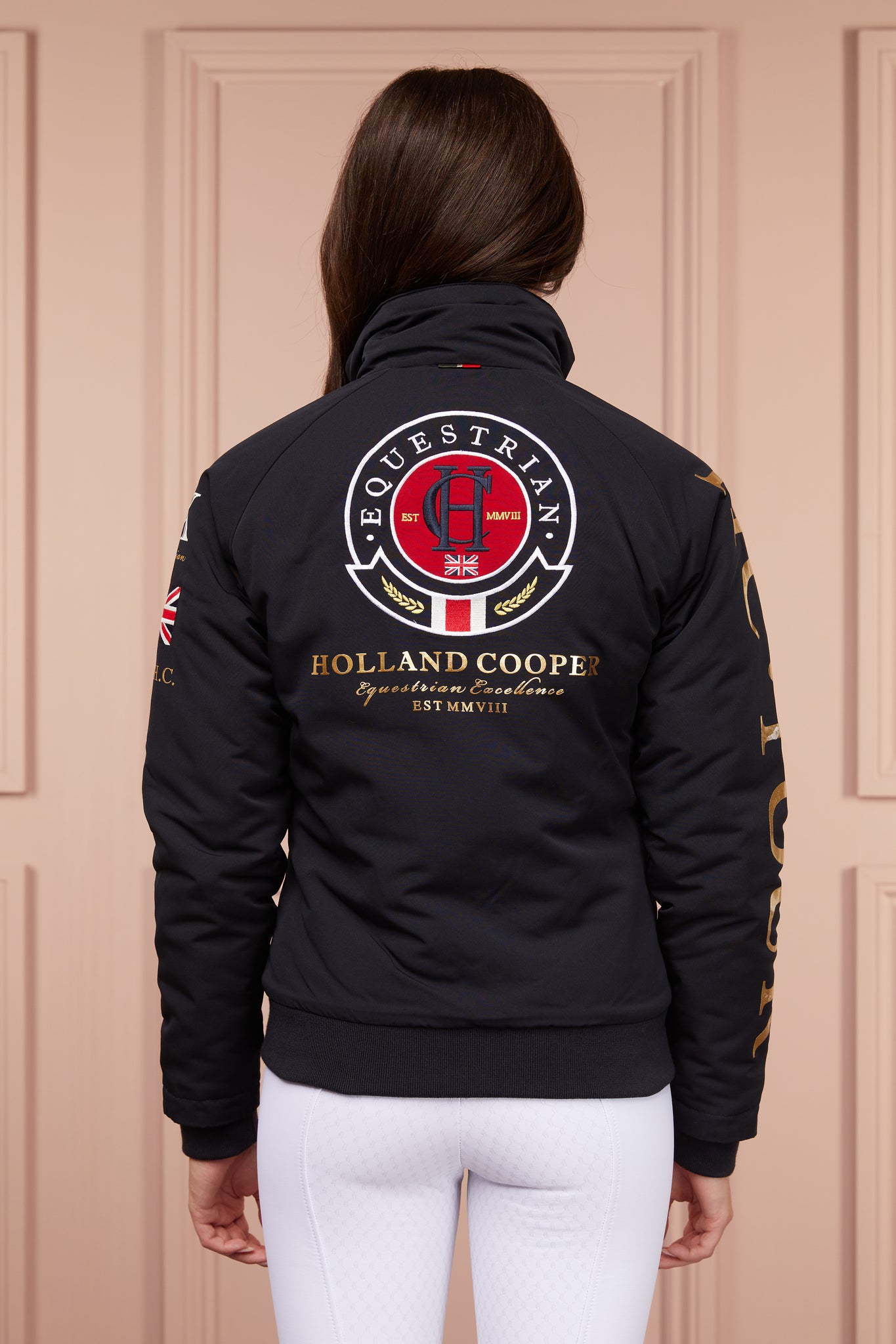 womens bomber style water resistant riding jacket in navy lined with fleece with elasticated ribbed cuffs and hem and covered in holland cooper equestrian graphic prints