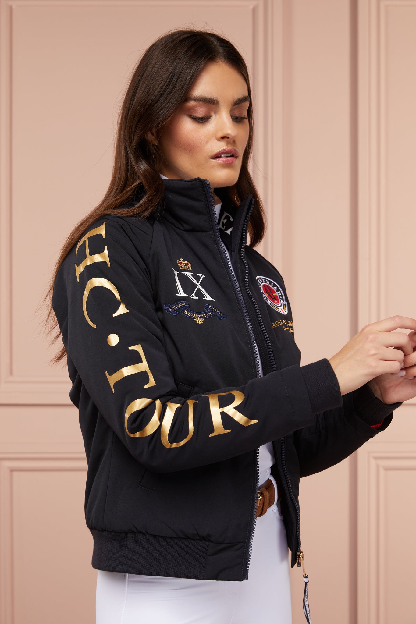 womens bomber style water resistant riding jacket in navy lined with fleece with elasticated ribbed cuffs and hem and covered in holland cooper equestrian graphic prints 