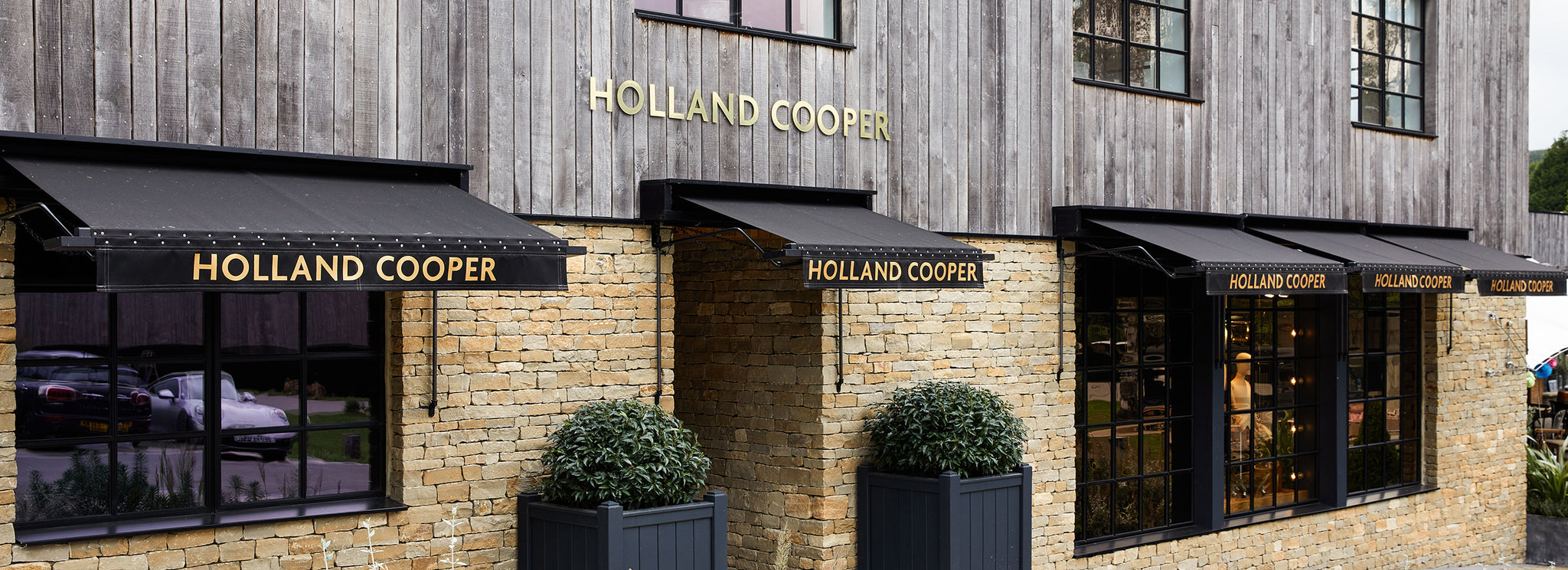 Holland Cooper Womens Boutique Store with gold lettering and cotswold yellow stone building with black glass window