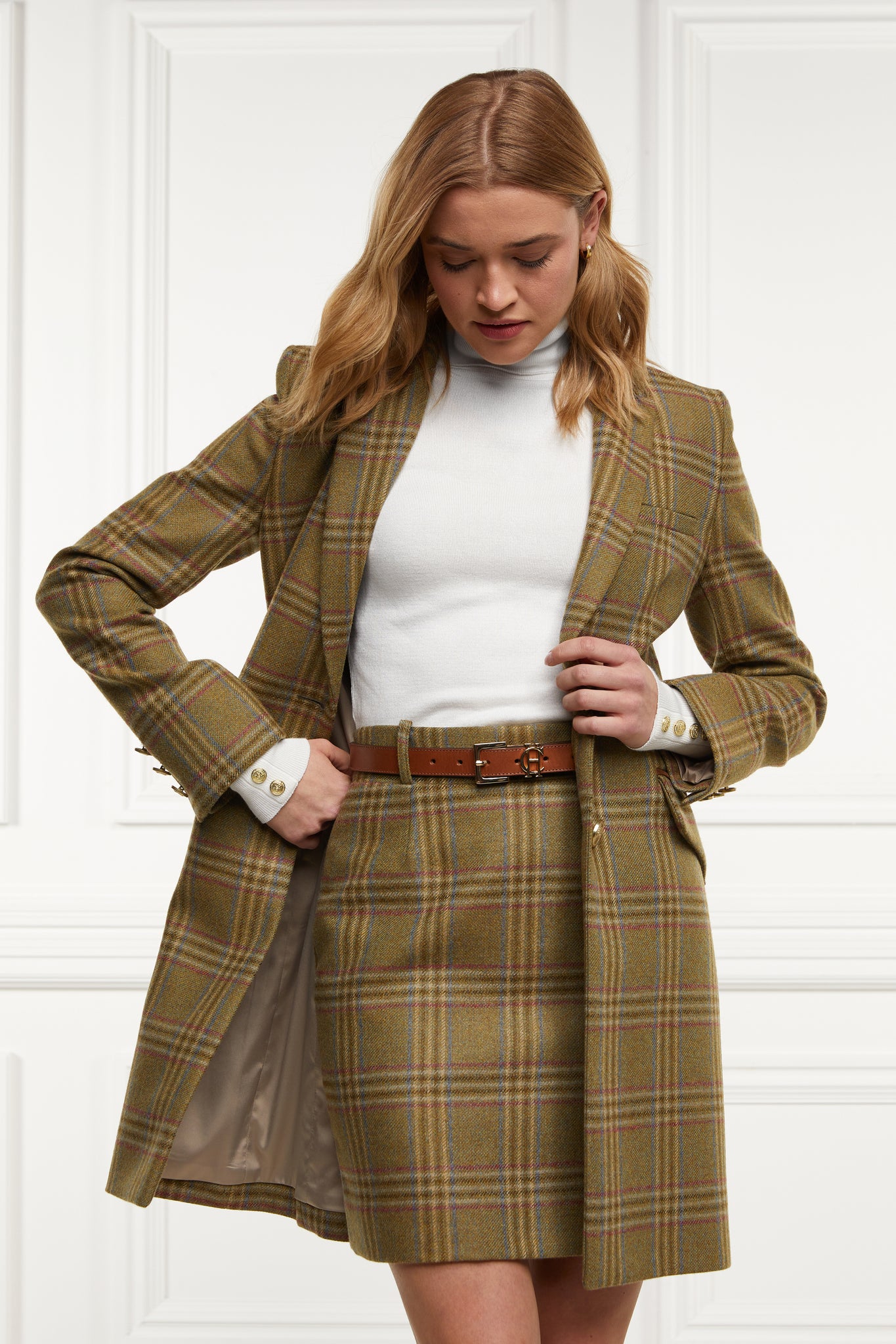 womens wool pencil mini skirt in green check with concealed zip fastening on centre back with gold hc button above zip worn with mid length single breasted coat in matching colourway