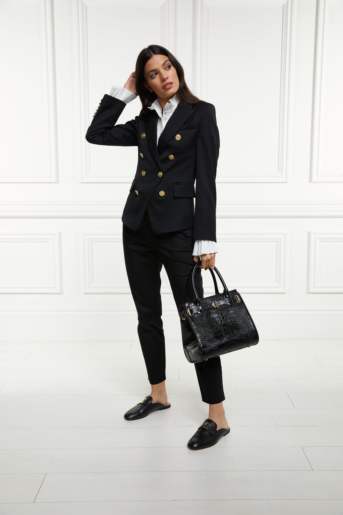 British made double breasted blazer that fastens with a single button hole to create a more form fitting silhouette with two pockets and gold button detailing this blazer is made from black barathea worn with white shirt black tailored trousers and a black tote bag