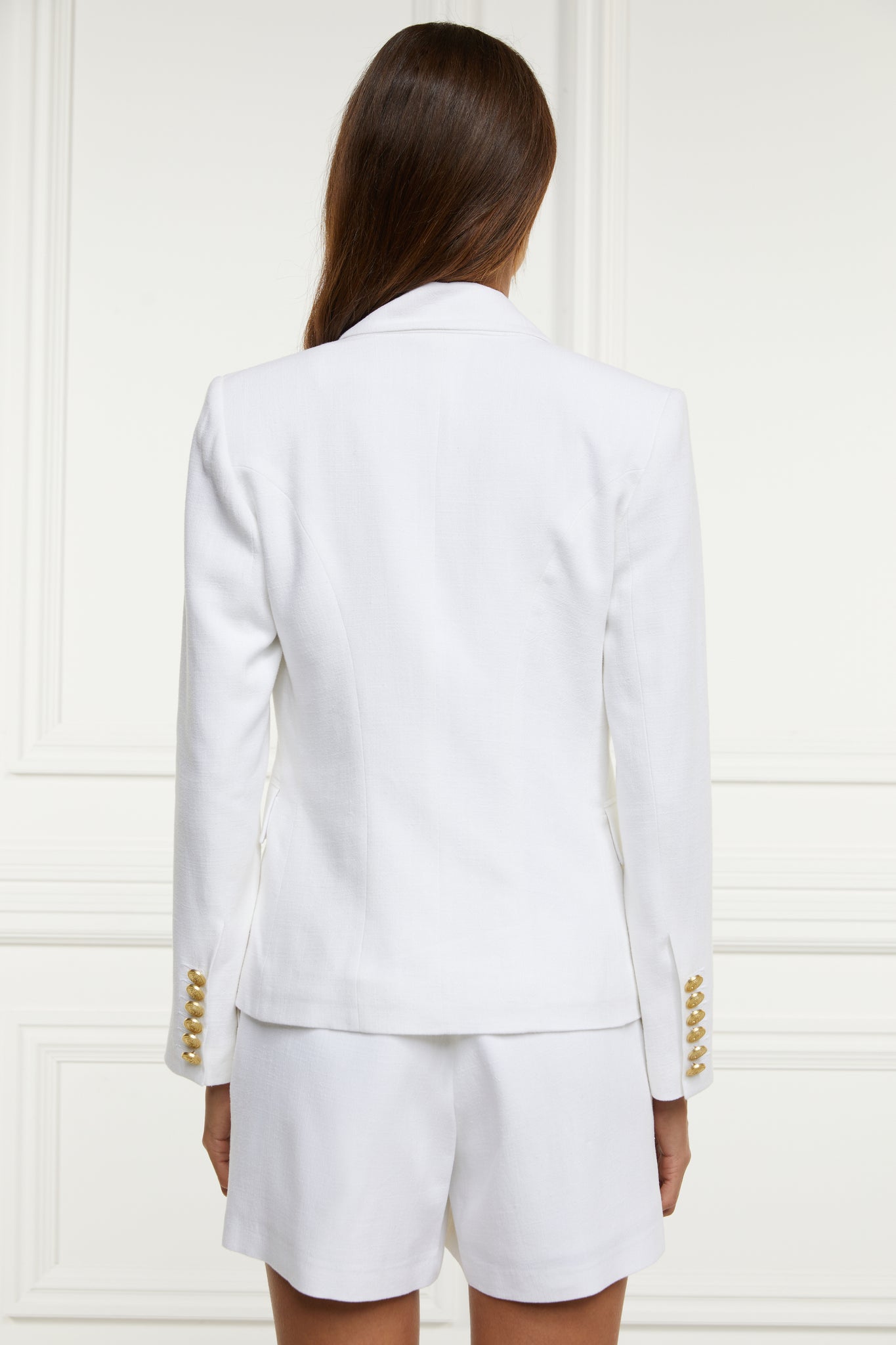 back of British made double breasted blazer that fastens with a single button hole to create a more form fitting silhouette with two pockets and gold button detailing this blazer in white linen