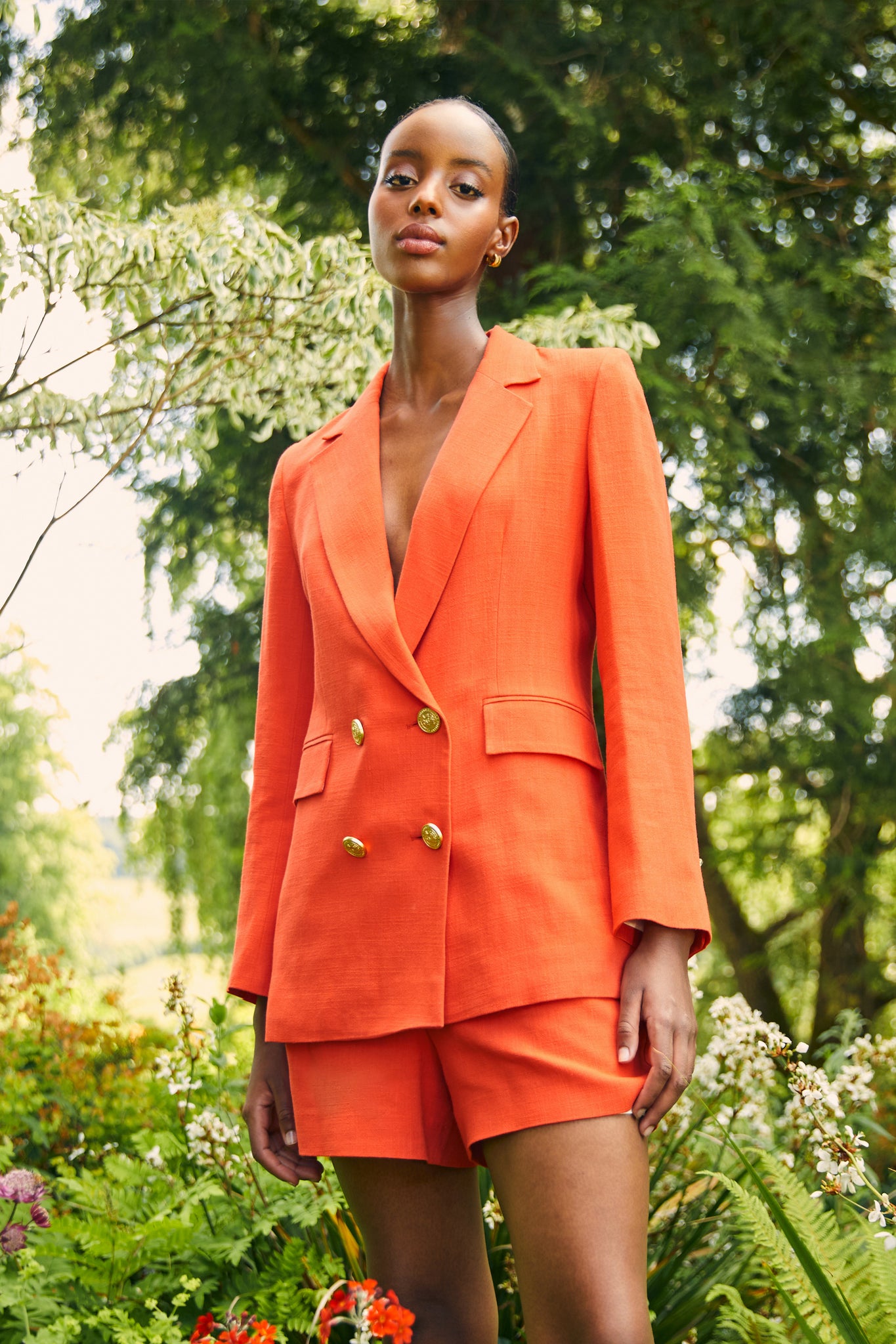 double breasted linen blazer in orange with two hip pockets and gold button detials down front and on cuffs and handmade in the uk worn with matching orange linen tailored shorts