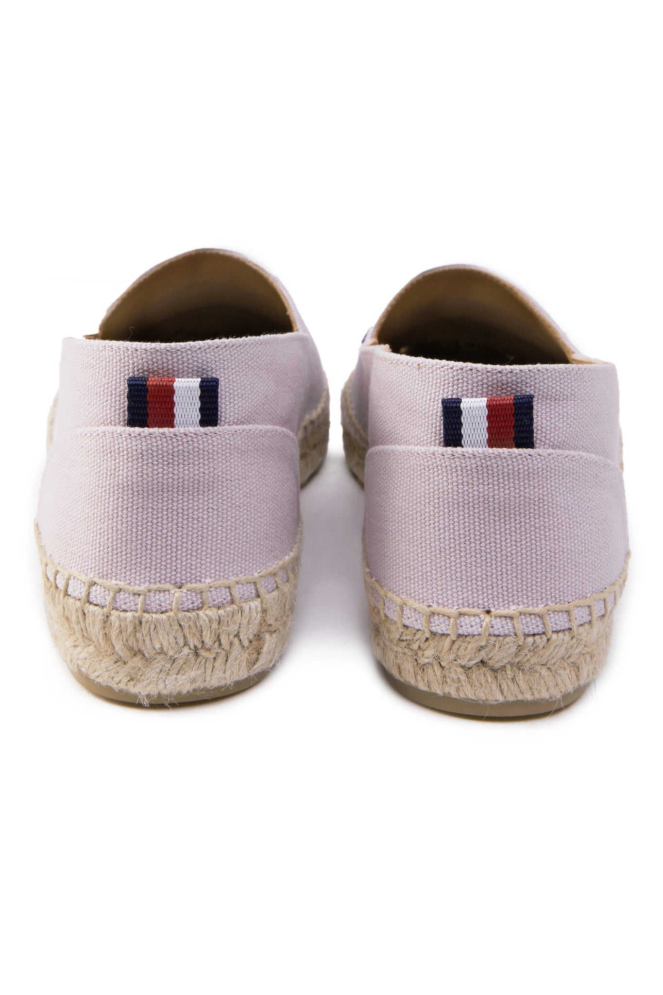 Back of classic style light pink canvas espadrille with plaited jute sole and jute toe cap with red white and blue small tag to the heel