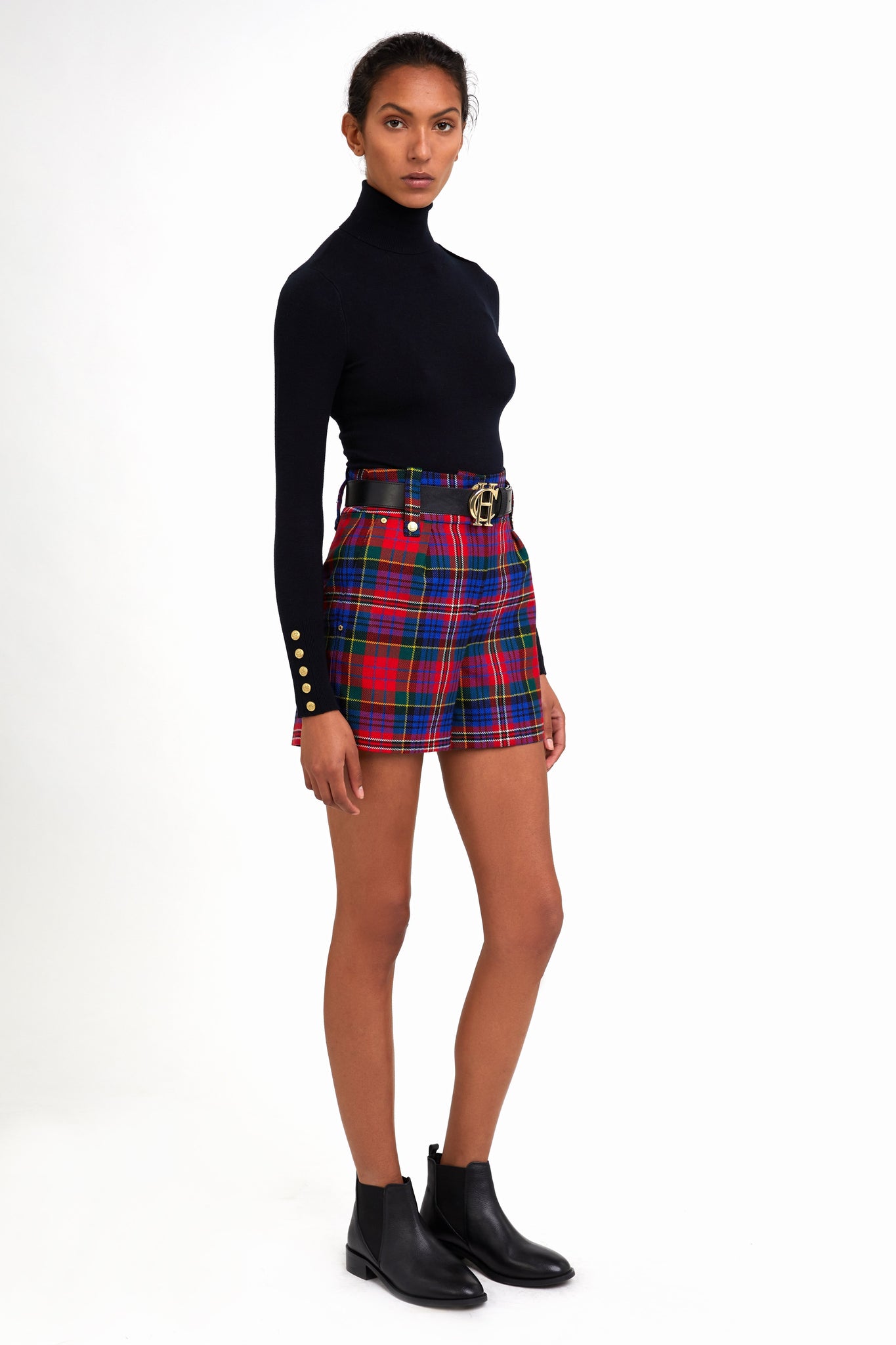 womens red blue and green tartan high rise tailored shorts with two single knife pleats and centre front zip fly fastening with twin branded gold stud buttons and side hip pockets with branded rivet detailing at top and bottom of pockets worn with black roll neck