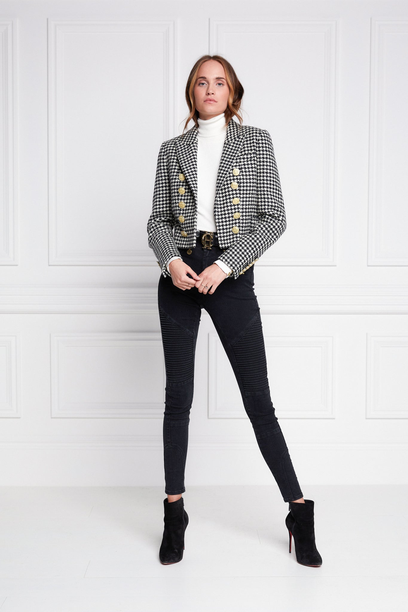 British made tailored cropped jacket in black and white houndstooth with welt pockets and gold button detail down the front and on sleeves worn with white roll neck and black skinny jeans 
