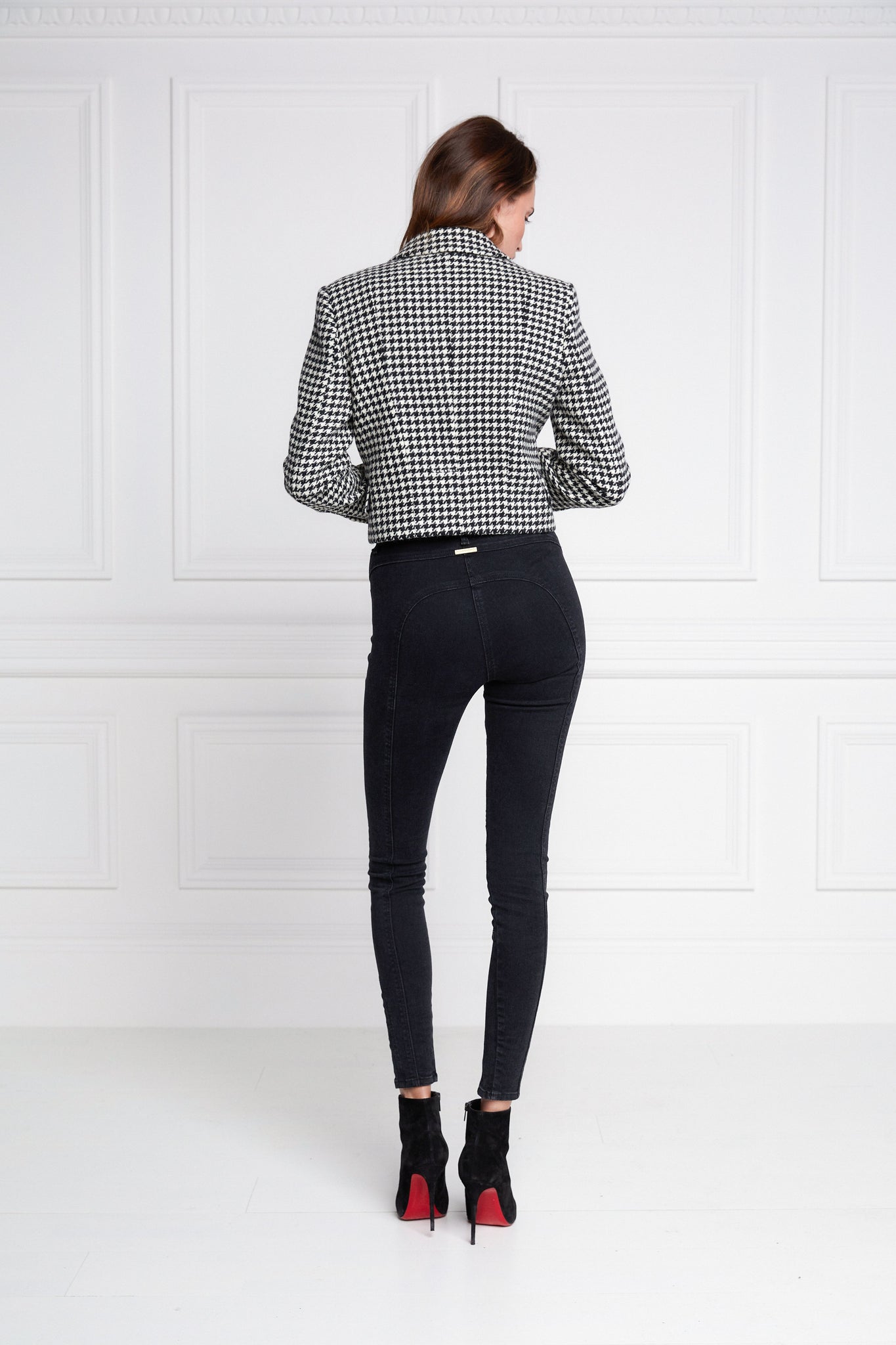 back of British made tailored cropped jacket in black and white houndstooth with welt pockets and gold button detail down the front and on sleeves