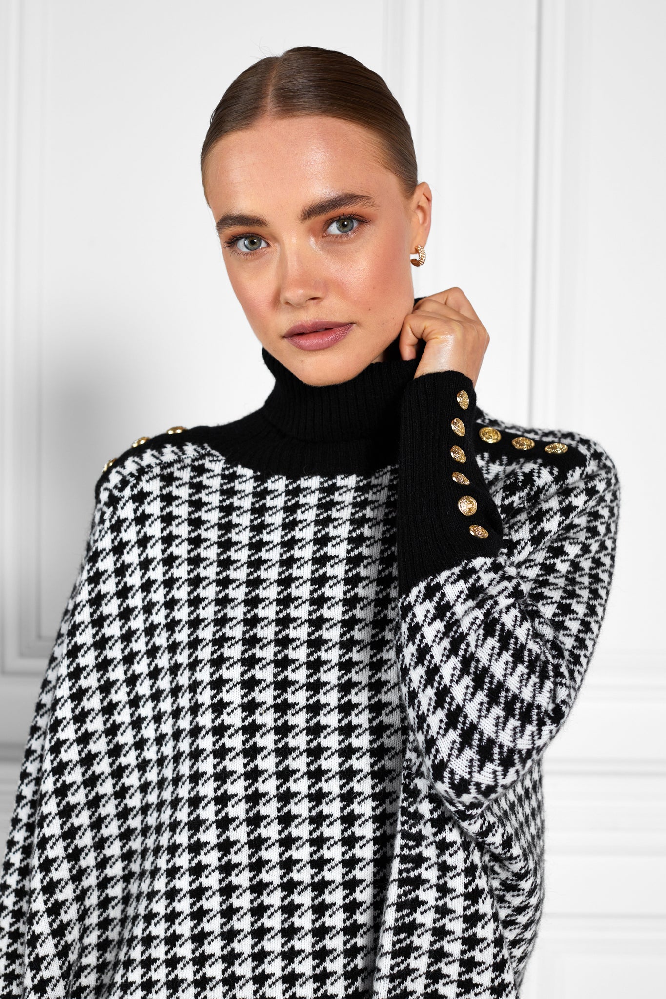 womens funnel neck batwing shaped cape in a white and black houndstooth knit with split side detail and contrast black neckline cuffs and hem