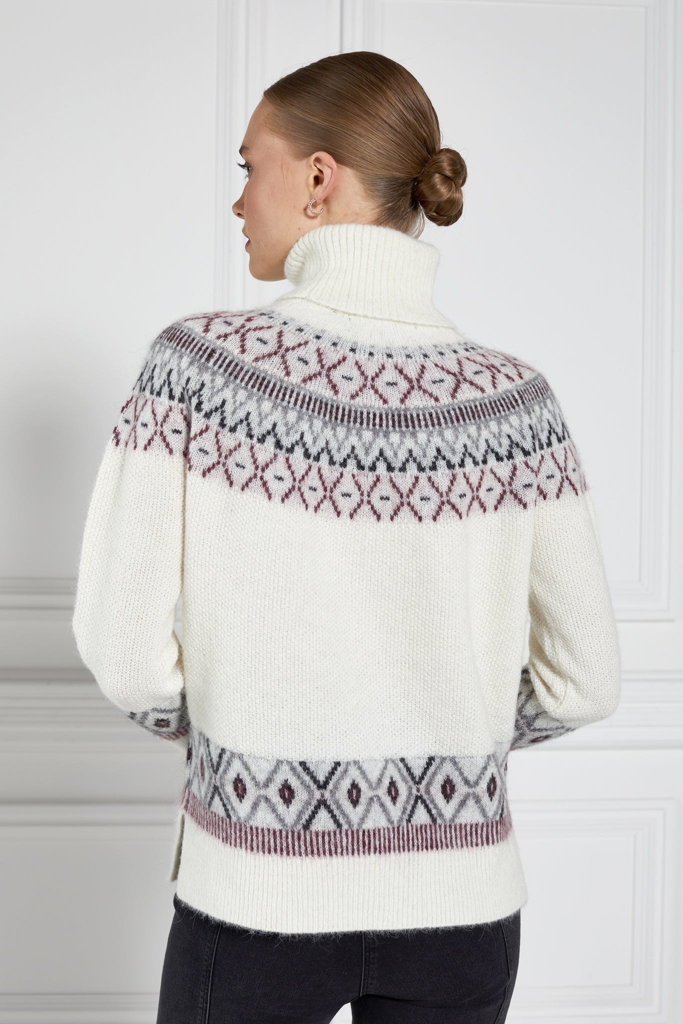 a classic cream roll neck jumper with fairisle knit in red and grey around the shoulders waistline and cuffs and a split ribbed hem 