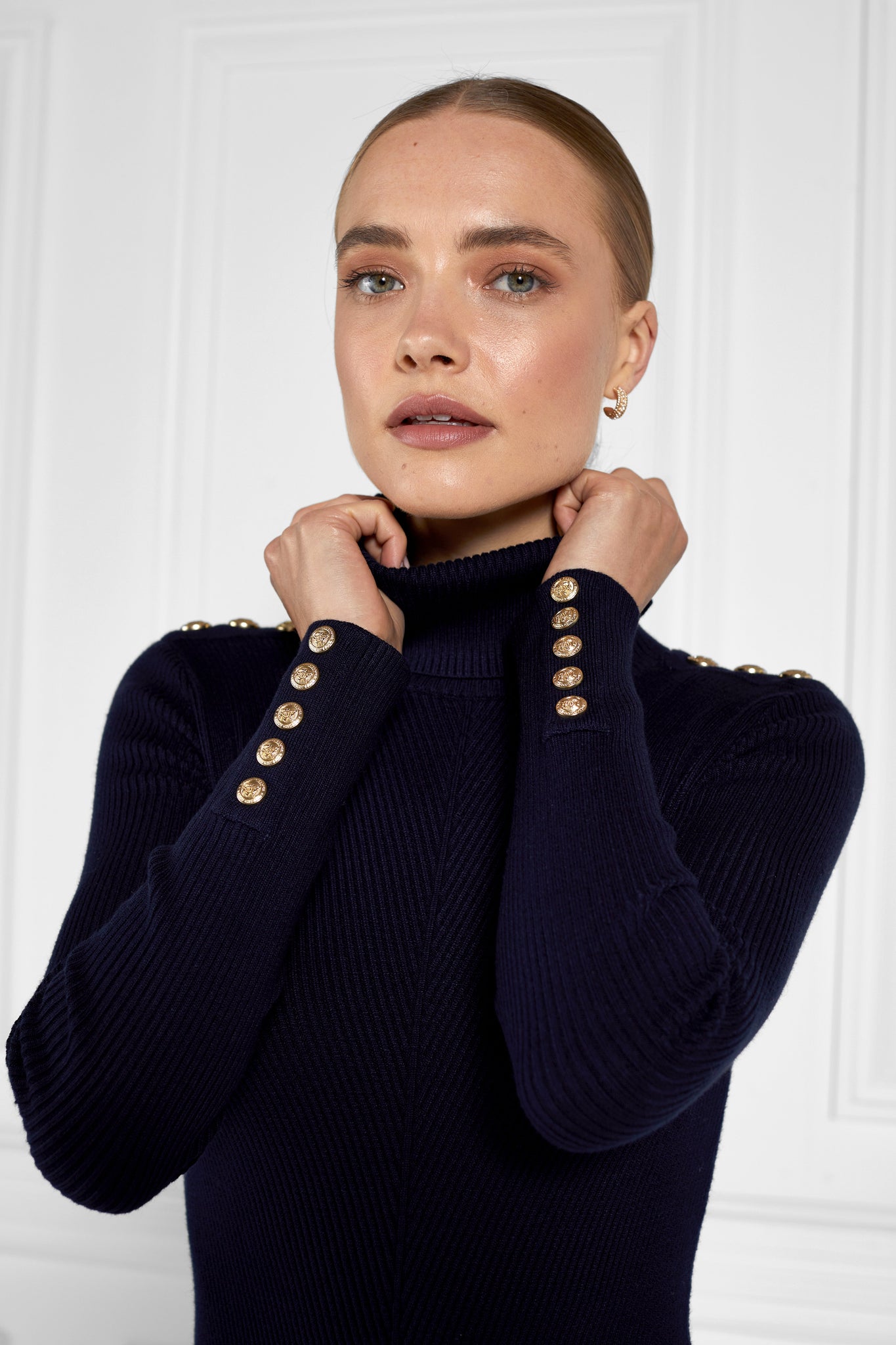 zoomed in shot of womens navy knitted roll neck midi dress with gold buttons on cuffs and shoulders
