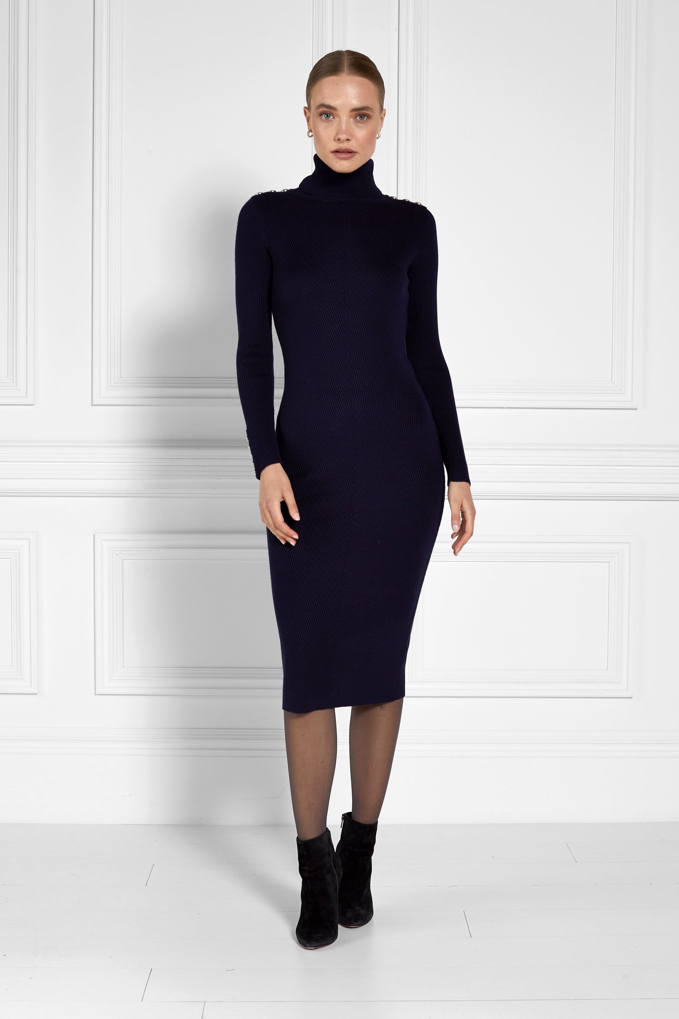 womens navy knitted roll neck midi dress with gold buttons on cuffs and shoulders with black heeled ankle boots