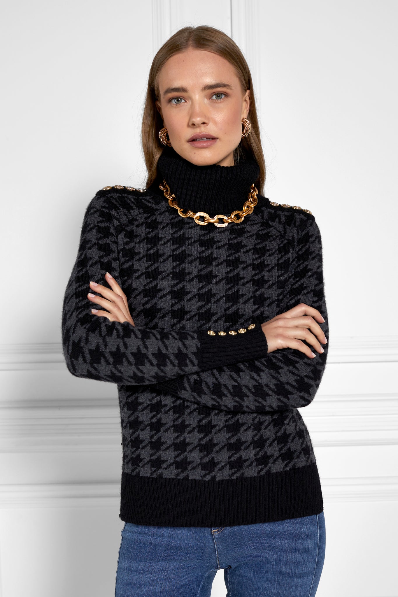 a classic black and grey houndstooth jumper with contrast black cuffs, roll neck and split ribbed hem with gold button detail on the cuffs and collar