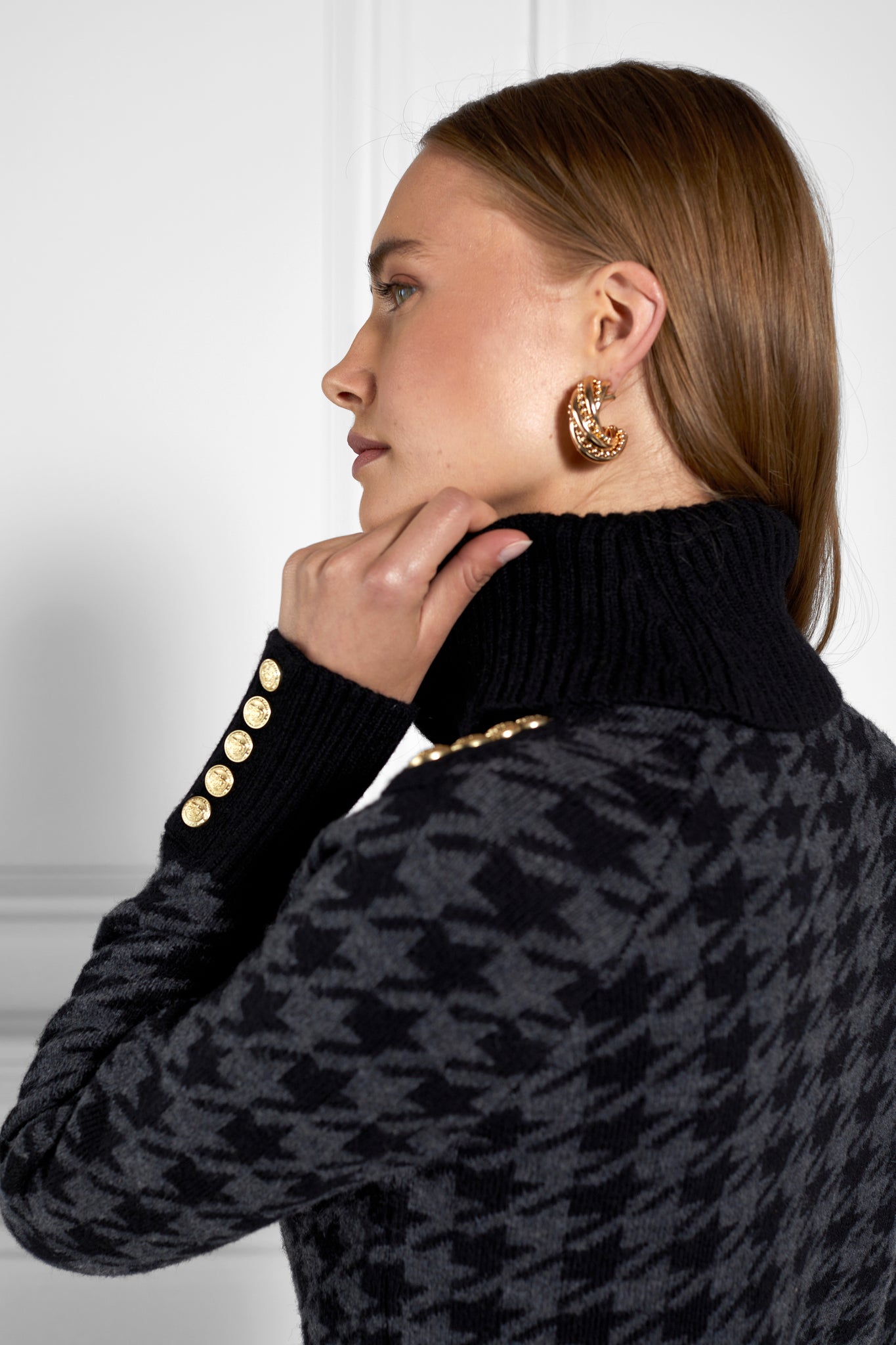 a classic black and grey houndstooth jumper with contrast black cuffs, roll neck and split ribbed hem with gold button detail on the cuffs and collar
