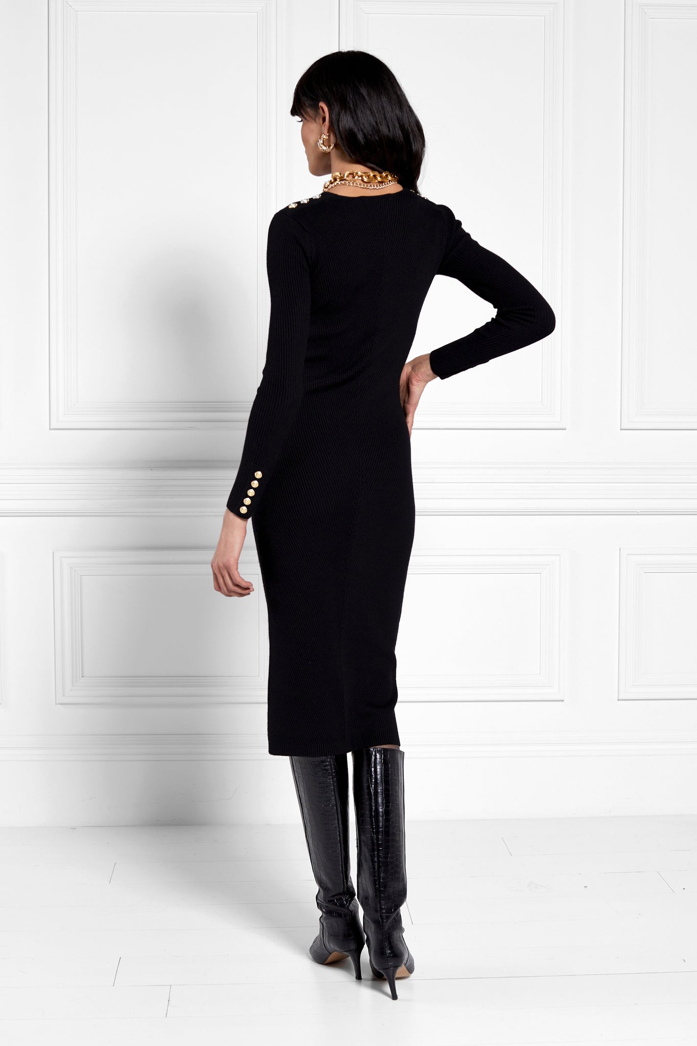 back shot of womens black long sleeve knitted v neck midi dress with gold buttons on cuffs and shoulders 